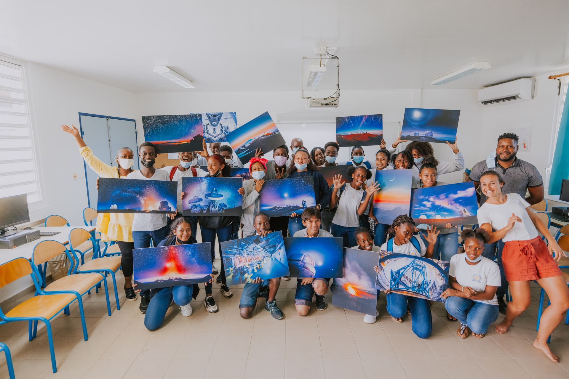 Un groupe de personnes pose pour une photo tout en tenant des tableaux dans une pièce.