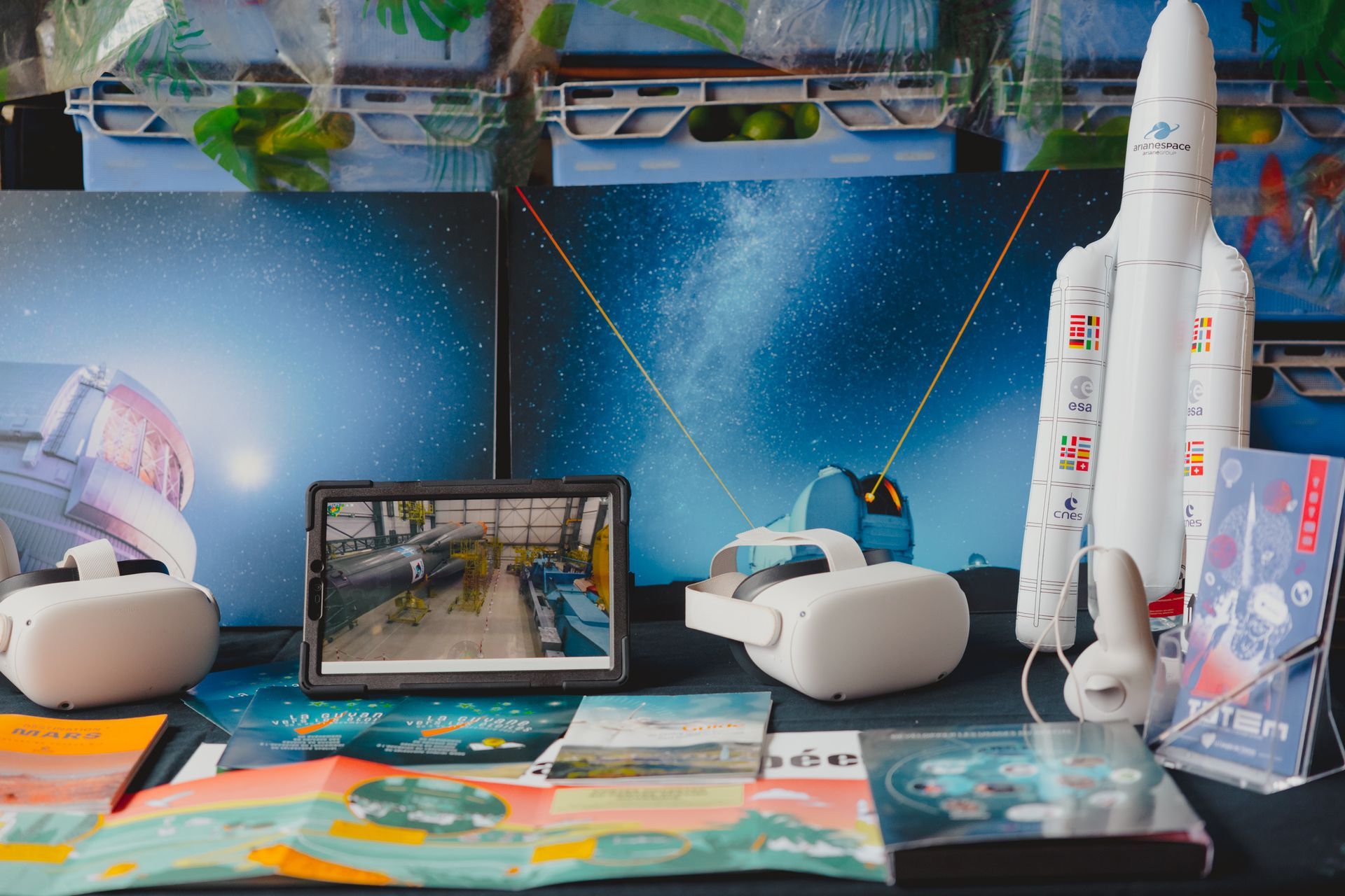 Une table avec une tablette, un casque de réalité virtuelle et une fusée dessus.