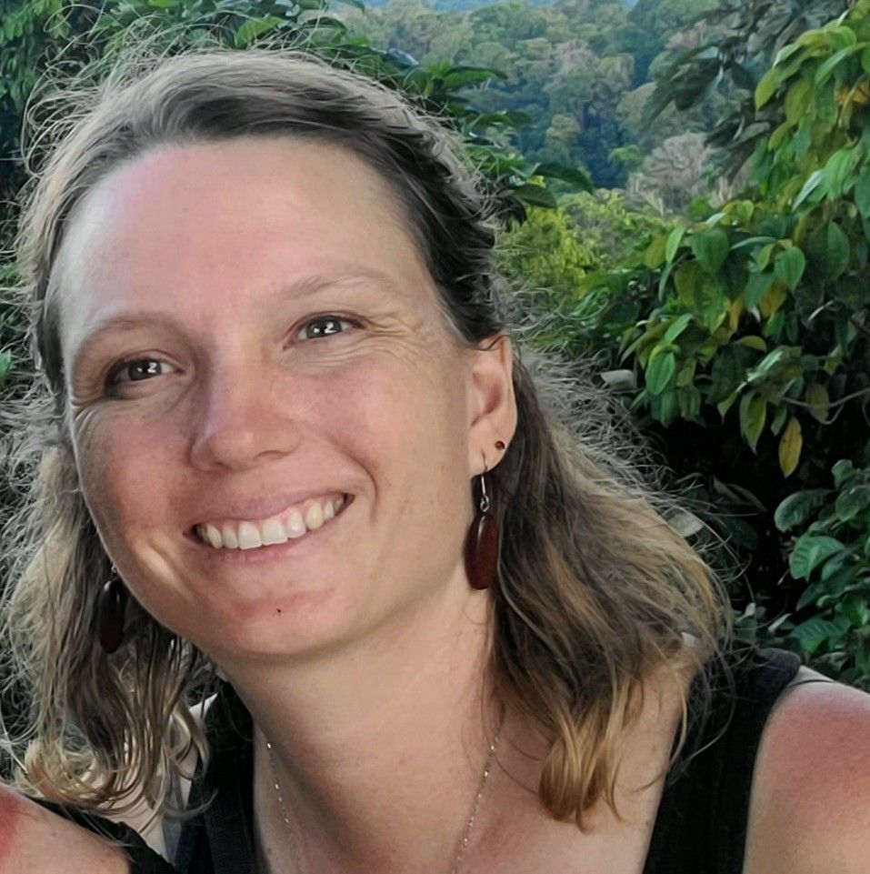 Une femme portant des lunettes de soleil se tient devant un bâtiment.