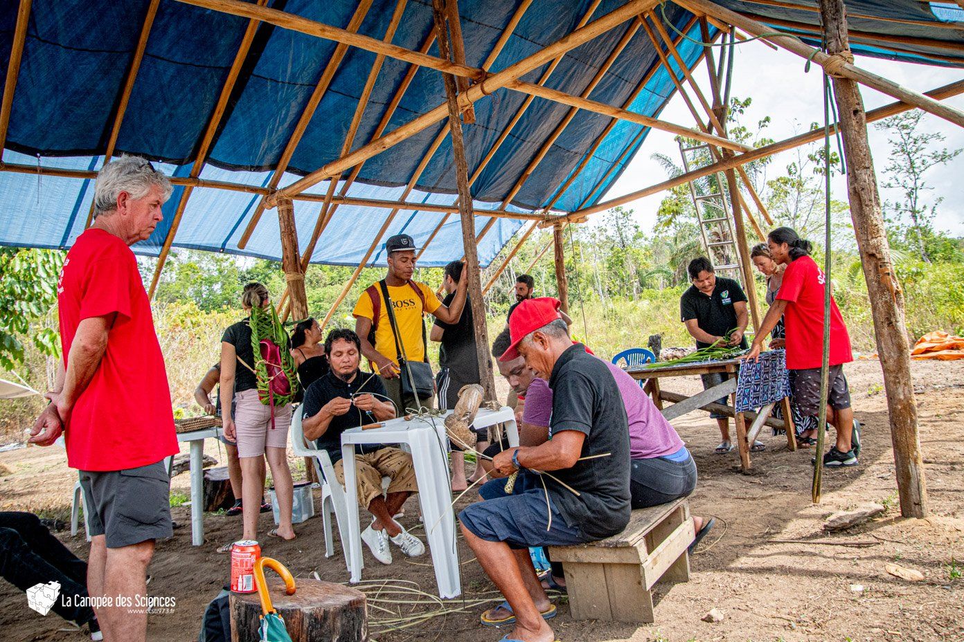 Un groupe de personnes est assis à des tables sous une tente.