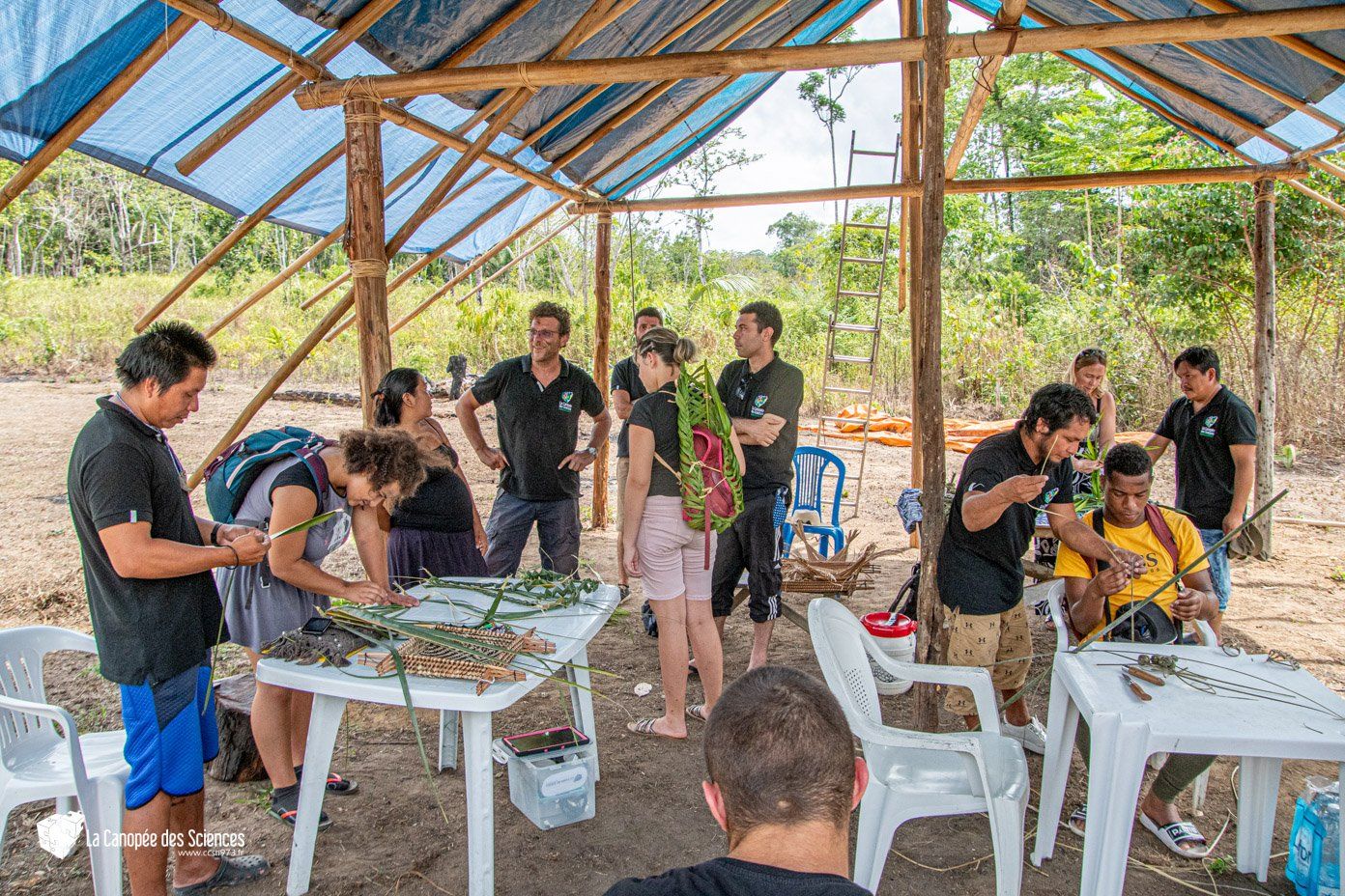 Un groupe de personnes se tient autour de tables sous un auvent.