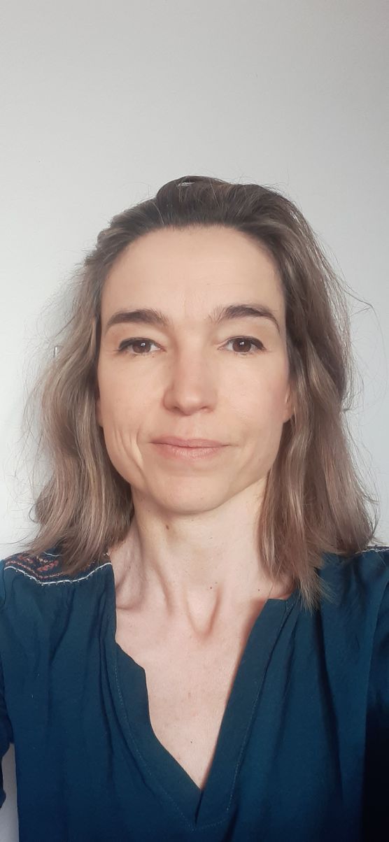 Une femme en chemise bleue sourit à la caméra.