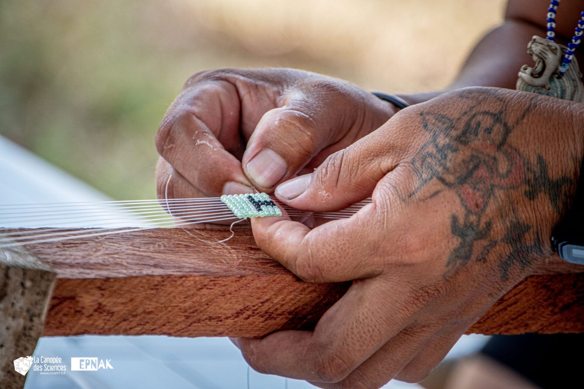 Une personne avec un tatouage sur la main travaille sur un morceau de bois.