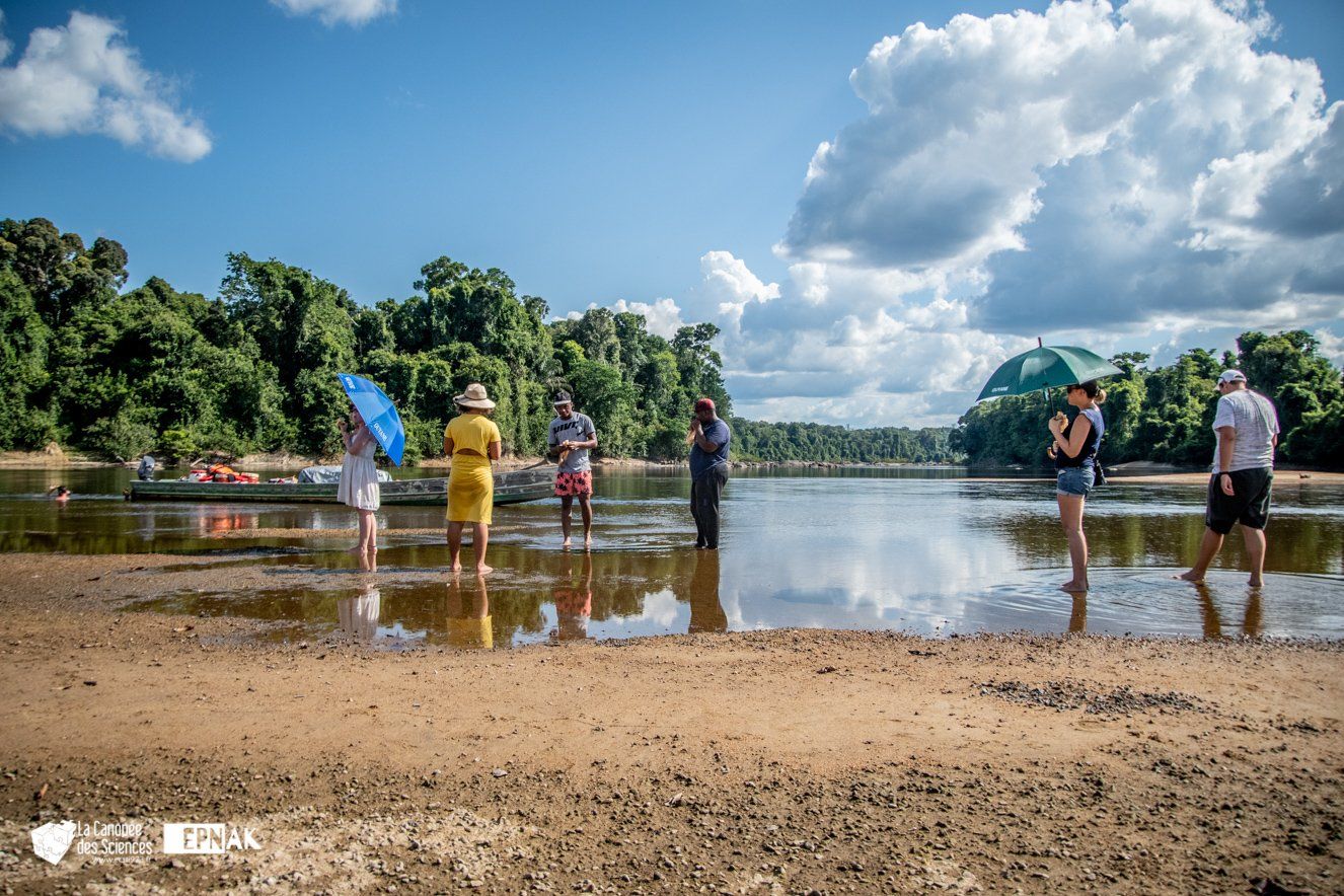 Un groupe de personnes se tient debout dans l'eau sur une plage.