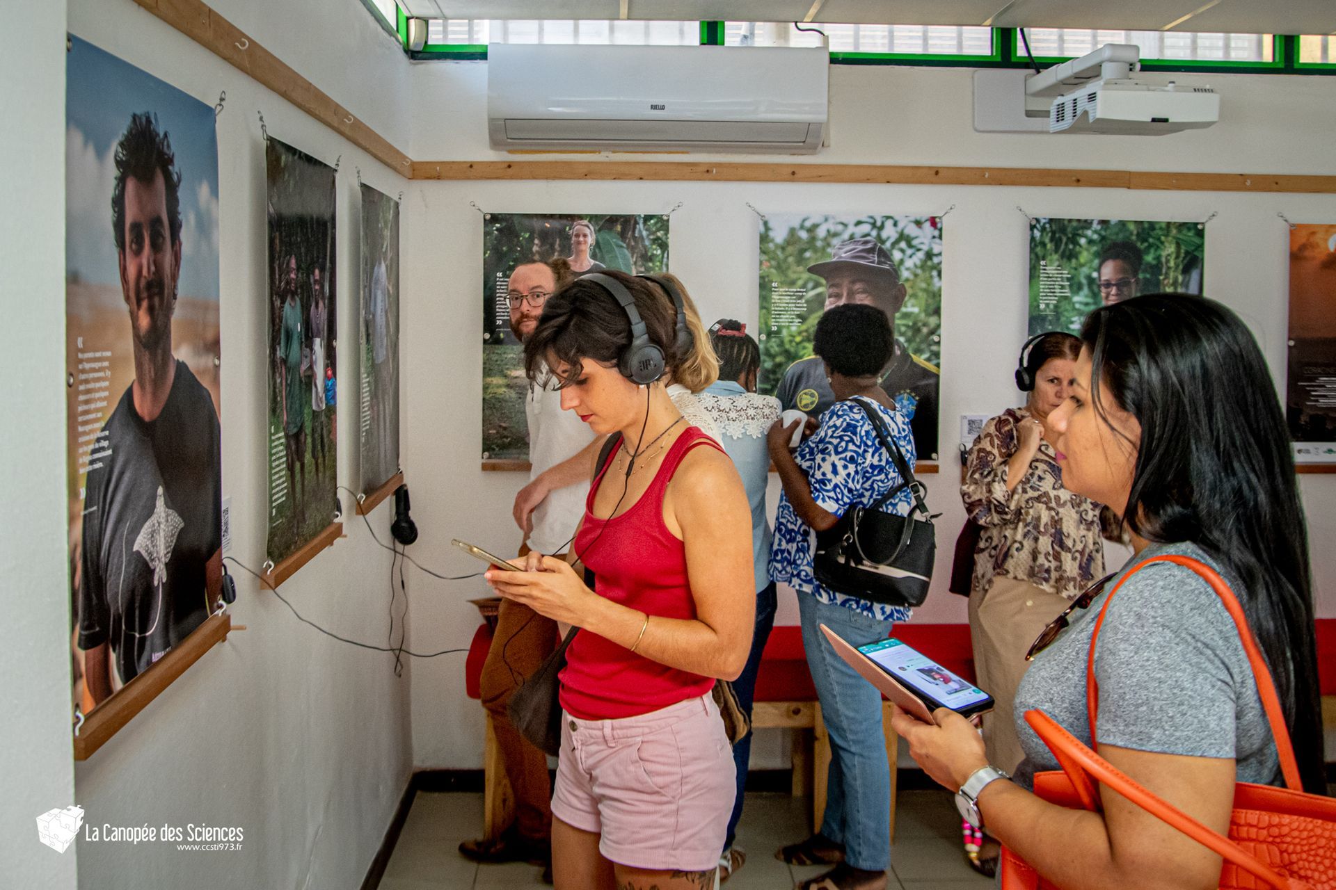 Un groupe de personnes se tient debout dans une pièce et regarde des images sur le mur.