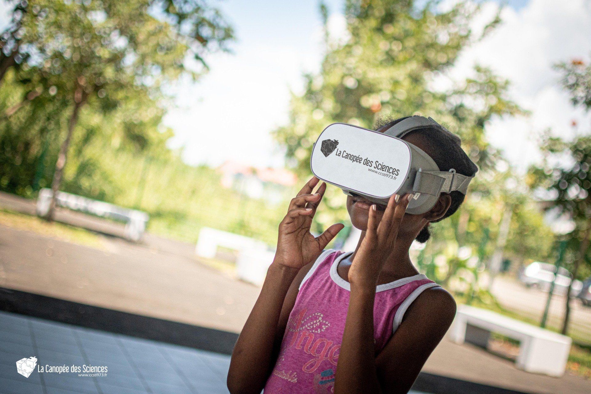 Une jeune fille portant un casque de réalité virtuelle dans un parc.