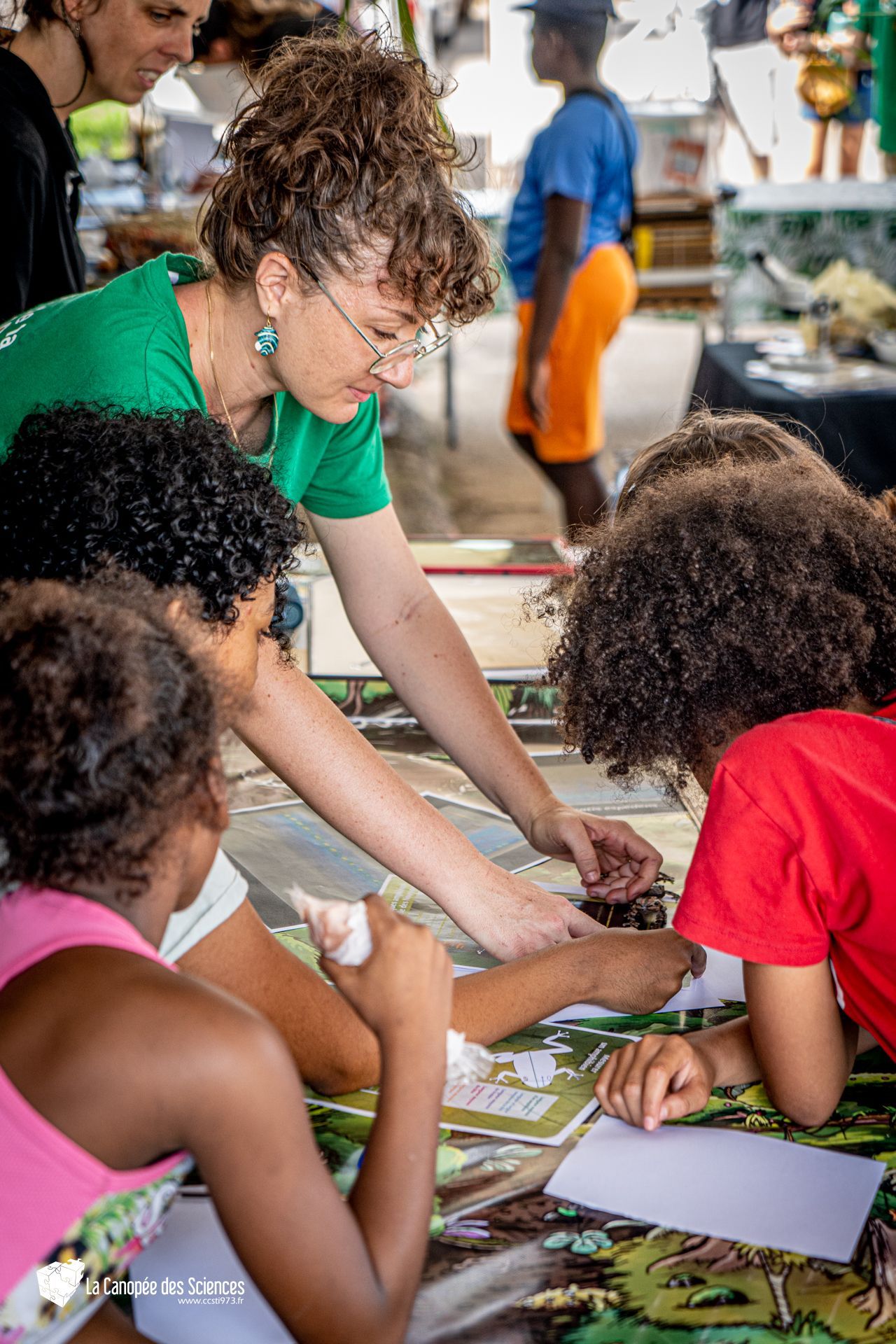 Un groupe d'enfants sont assis autour d'une table avec une femme qui les aide.