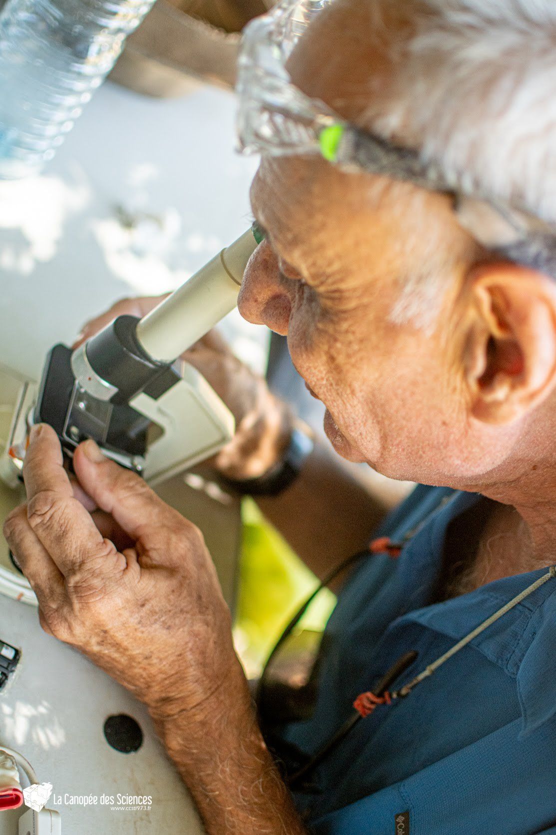 Un homme plus âgé regarde à travers un microscope.