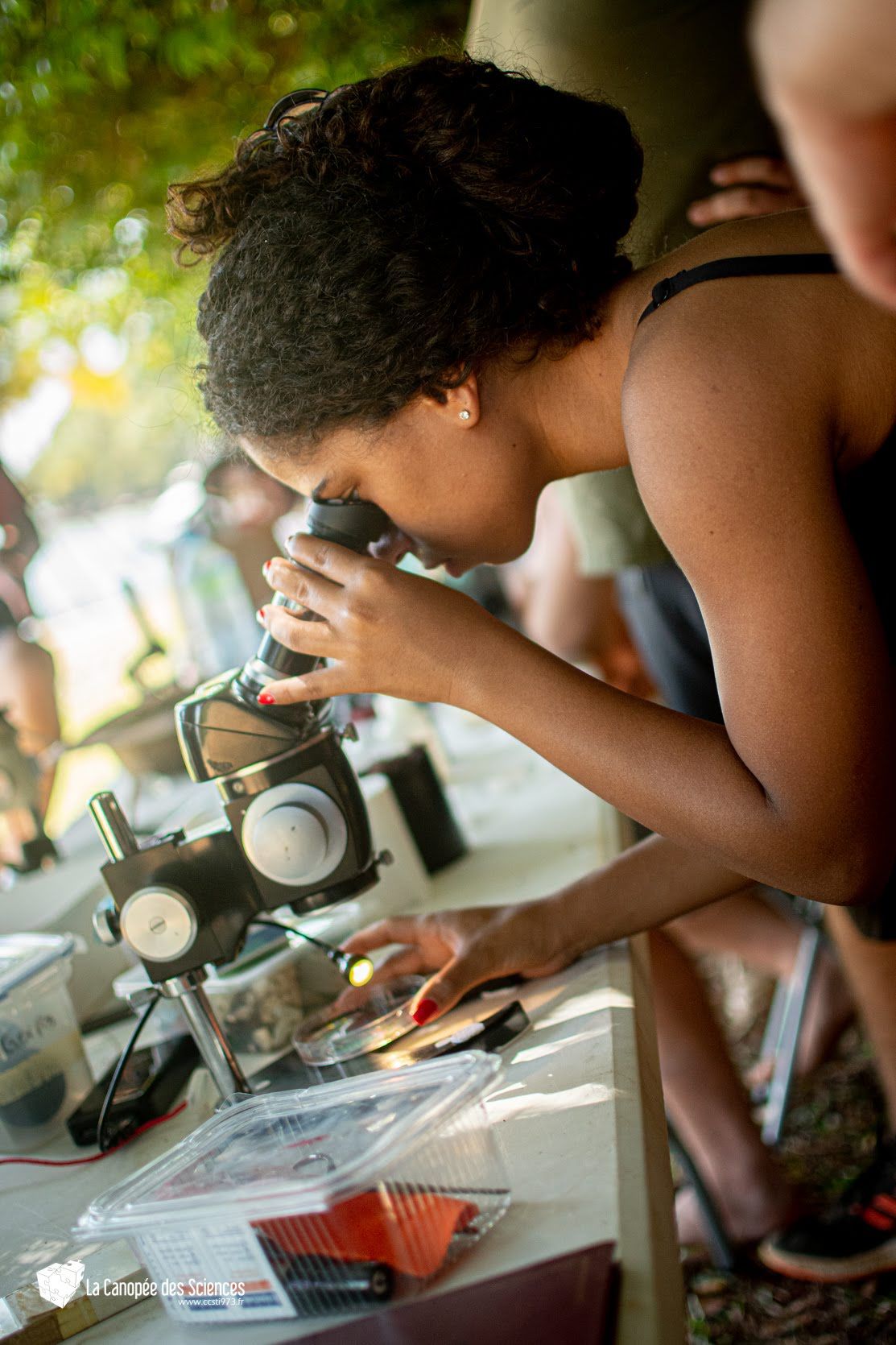 Une femme regarde quelque chose à travers un microscope.