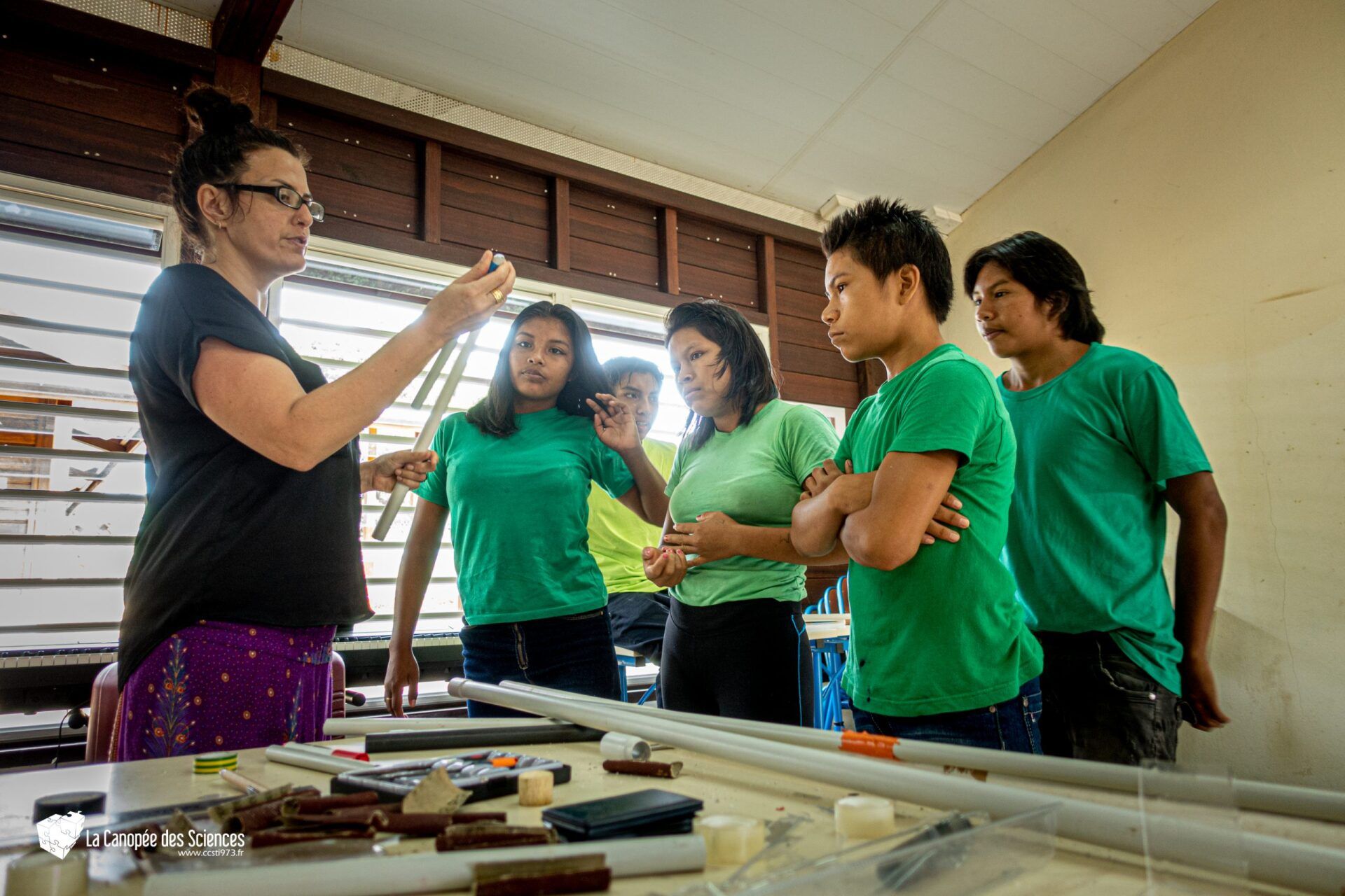 Un groupe de personnes en chemises vertes se tiennent autour d'une table.