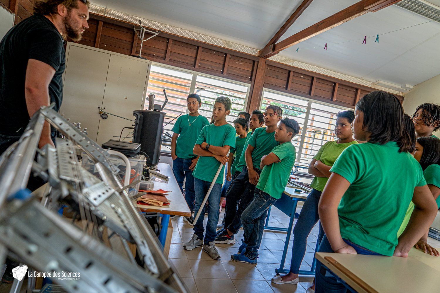 Un groupe de personnes en chemises vertes se tiennent dans une salle de classe.