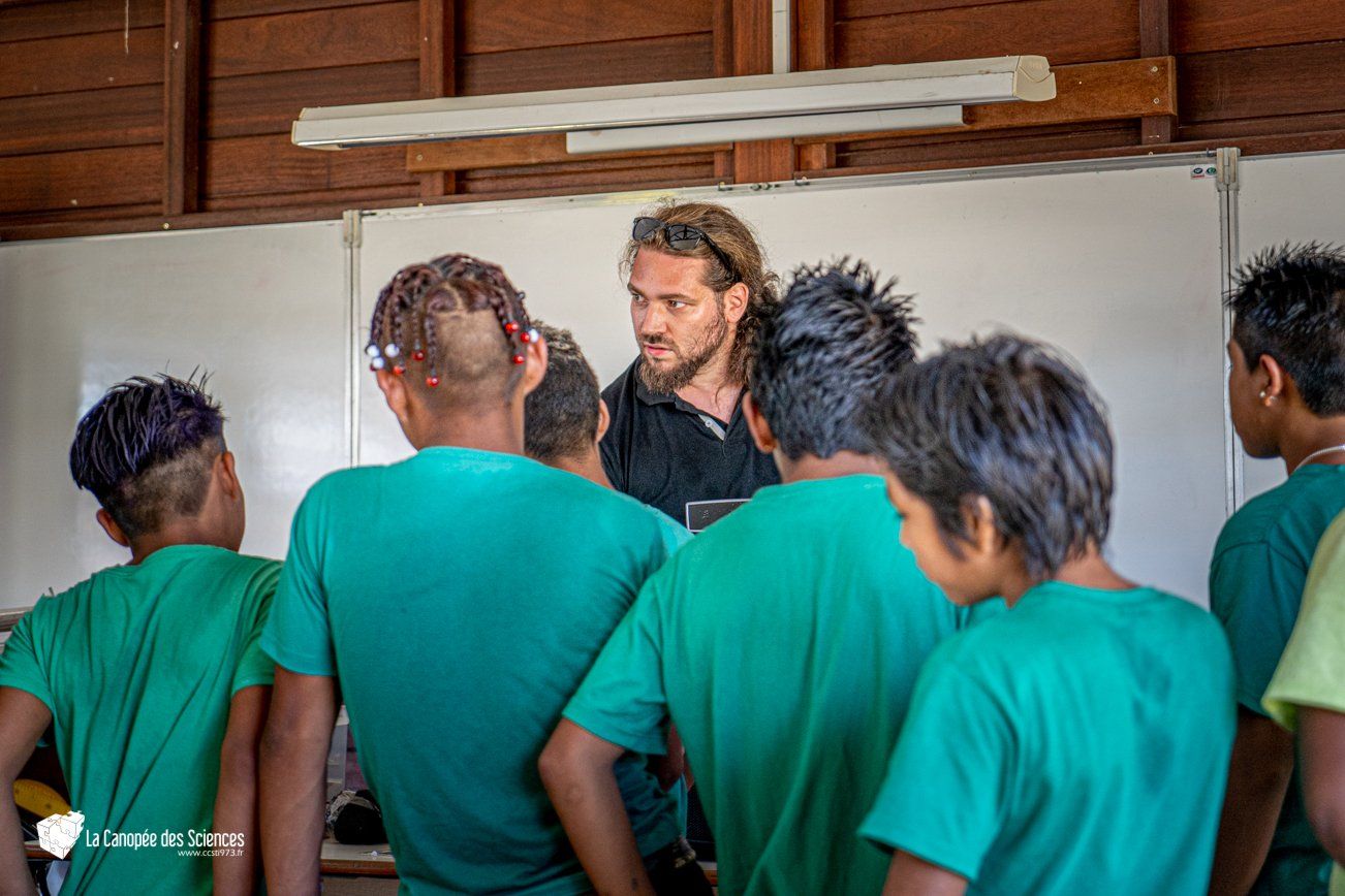 Un homme parle à un groupe de jeunes garçons dans une salle de classe.