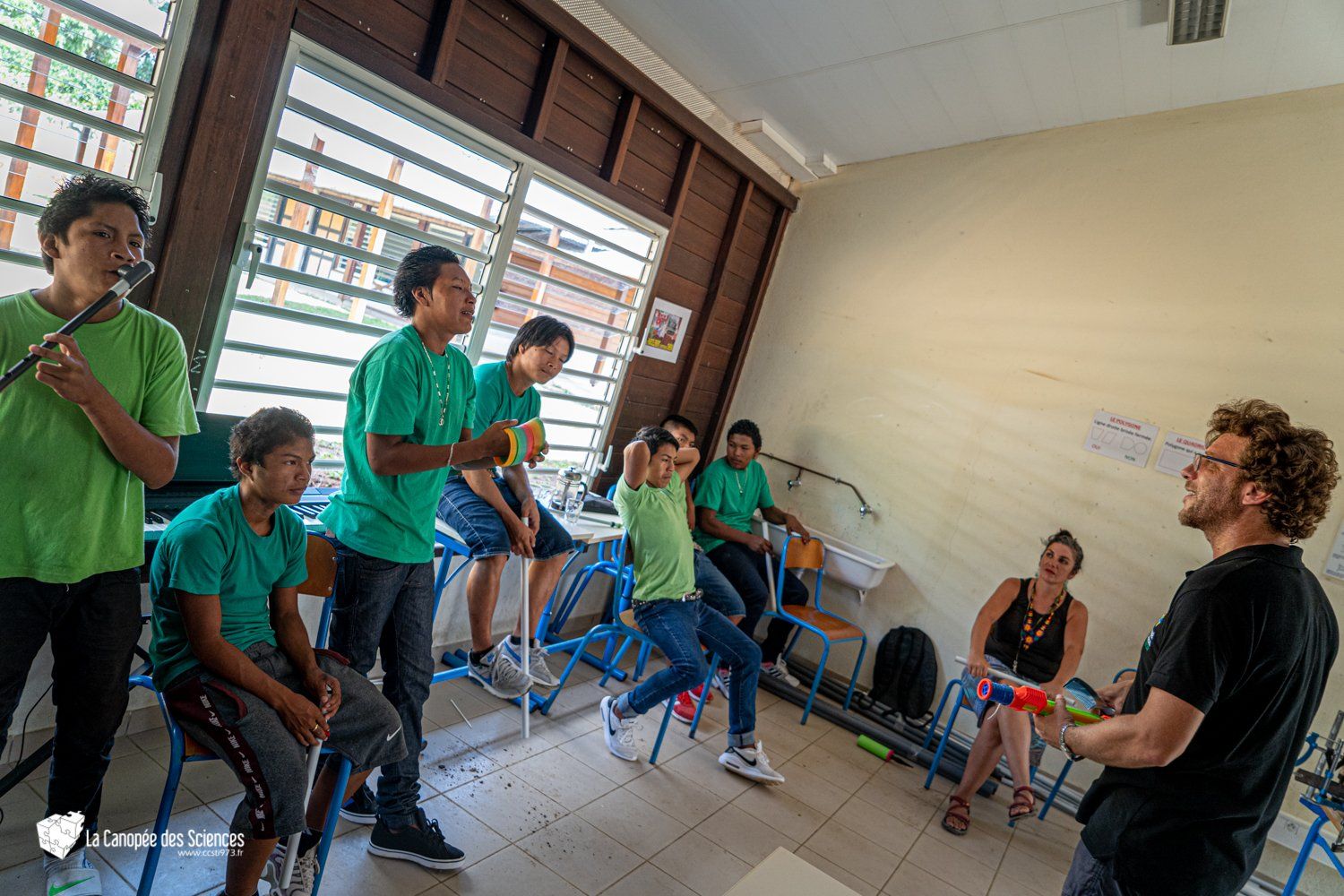 Un groupe d'enfants est assis autour d'un homme dans une salle de classe.