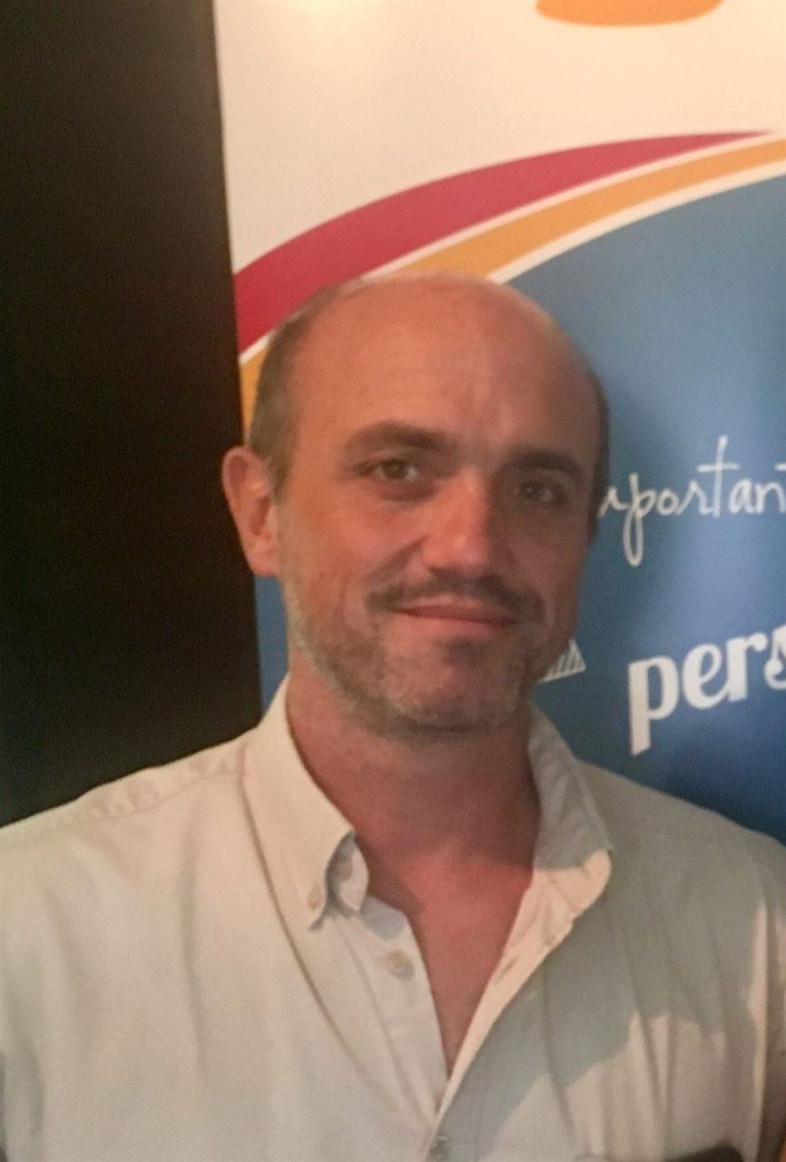 Un homme chauve se tient devant un panneau indiquant pers