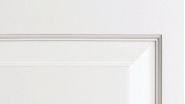 A close up of a white door with a white trim.