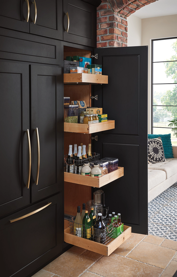 A kitchen with black cabinets and a pull out pantry filled with bottles.