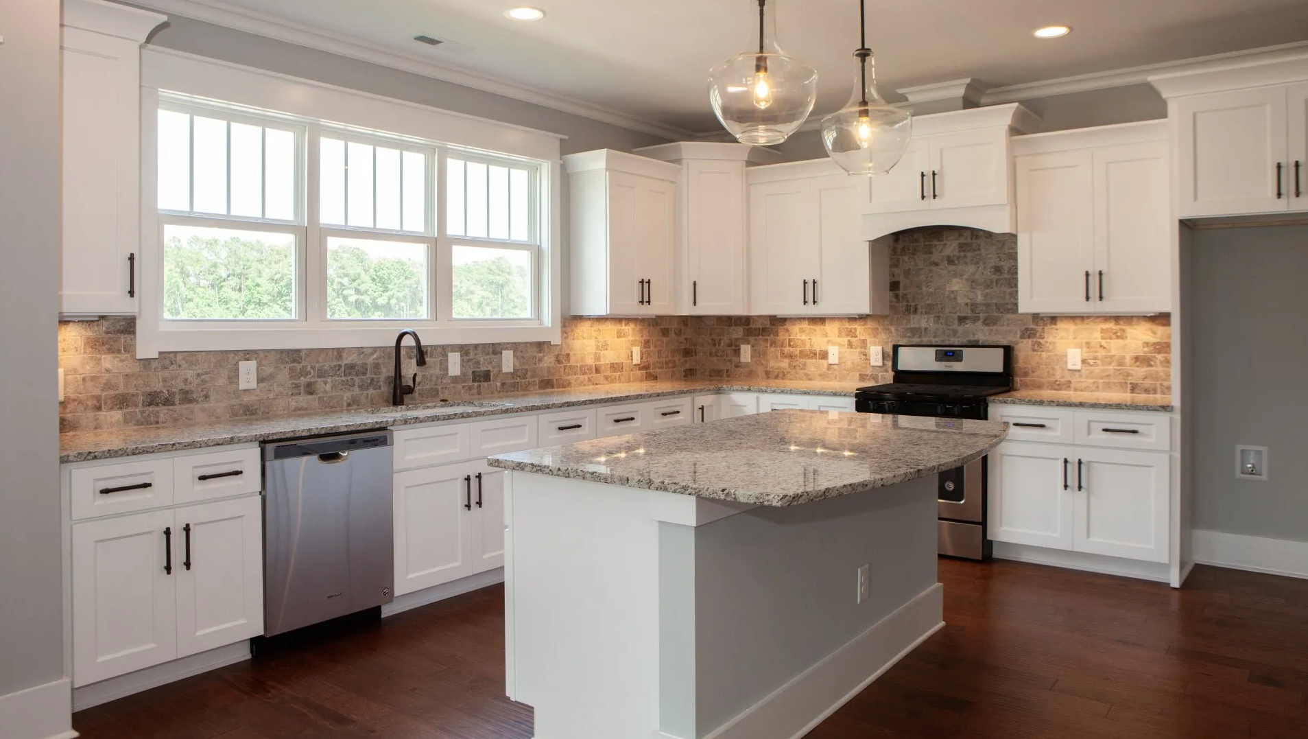 A kitchen with white cabinets , granite counter tops , stainless steel appliances and a large island.