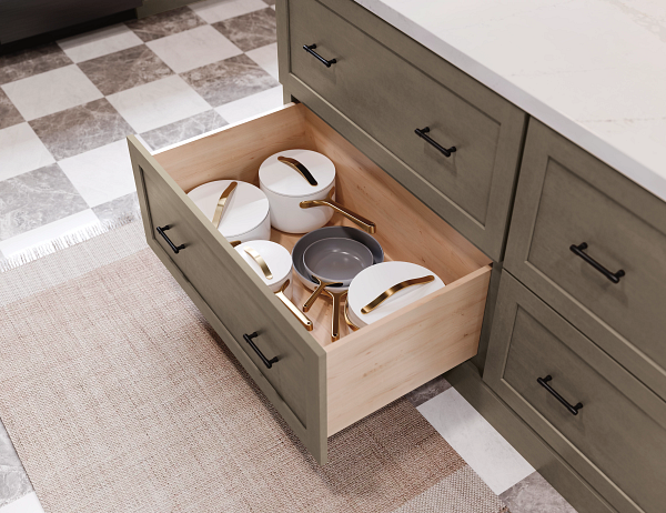 A kitchen drawer filled with pots and pans on a checkered floor.