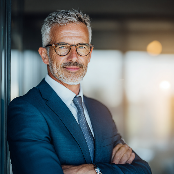 Família de três pessoas se abraçando ao ar livre, sorrindo; criança de camisa azul.