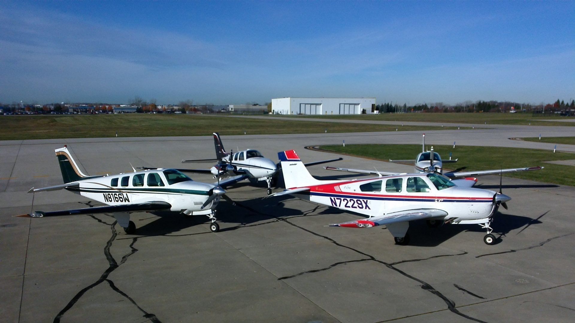 Two small planes are parked on a runway with one having the letters n324k on the tail