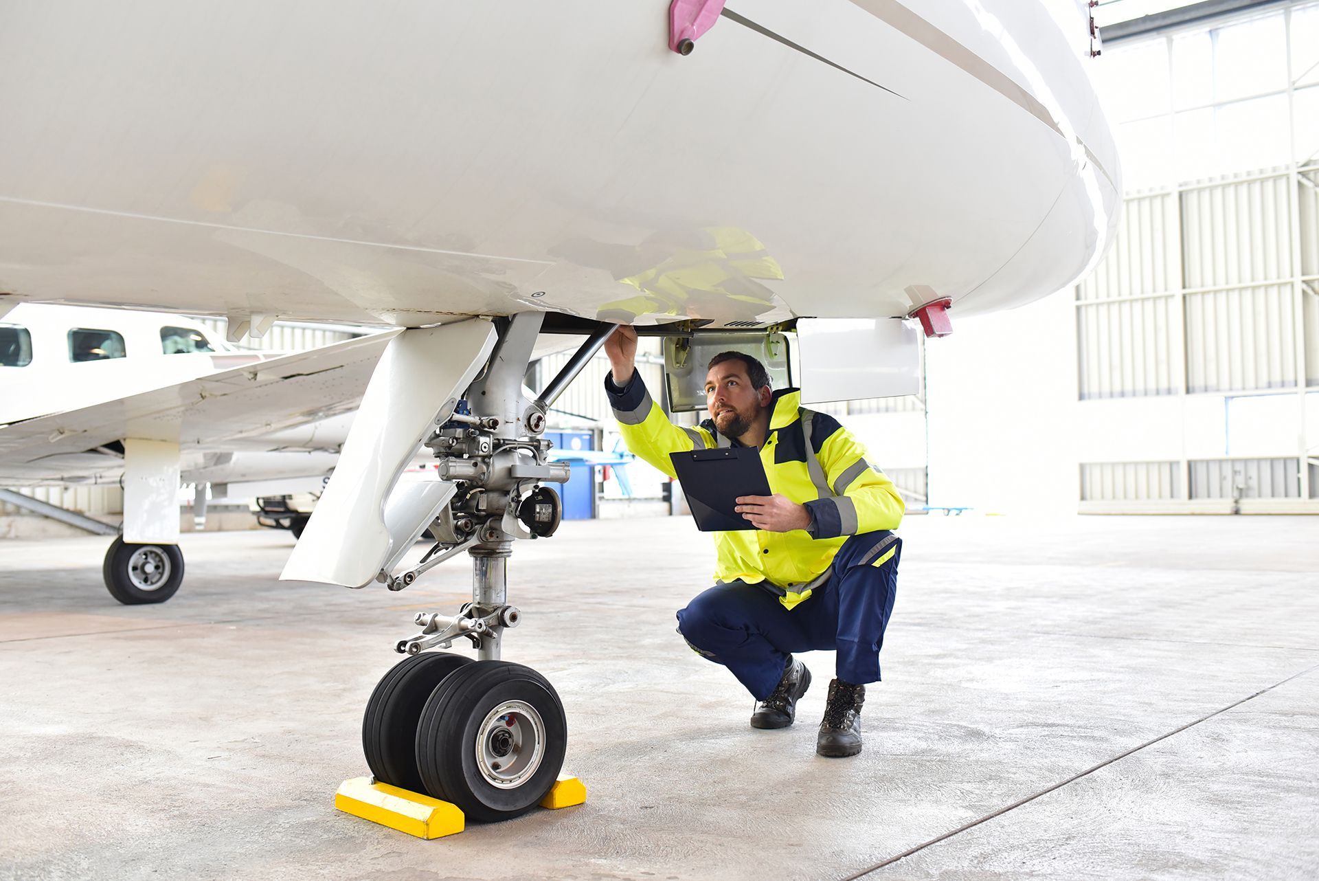 A man is working on a small airplane in a hangar.