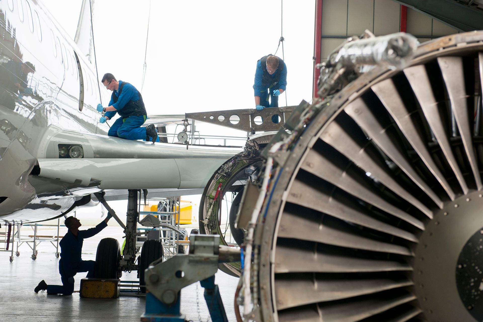 A group of men are working on an airplane in a hangar.