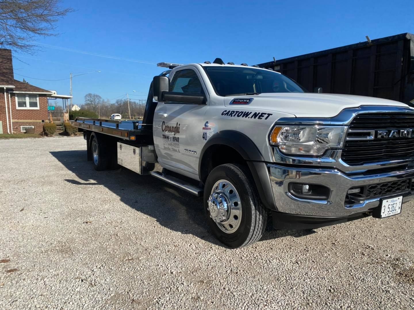 A white tow truck is parked in a gravel lot.