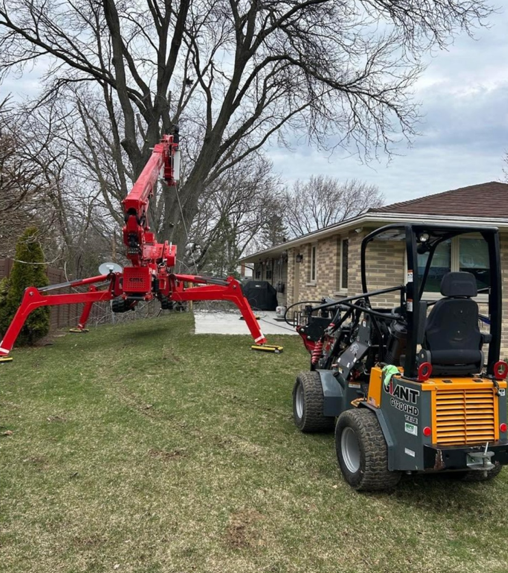 A tractor and a crane are parked in front of a house.