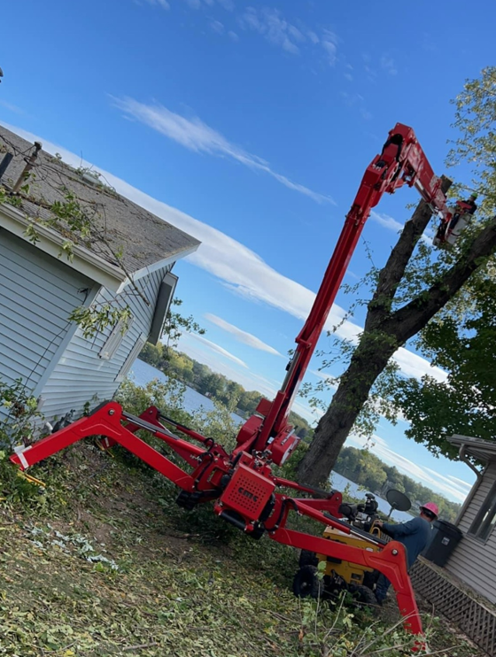A red crane is cutting a tree in front of a house.