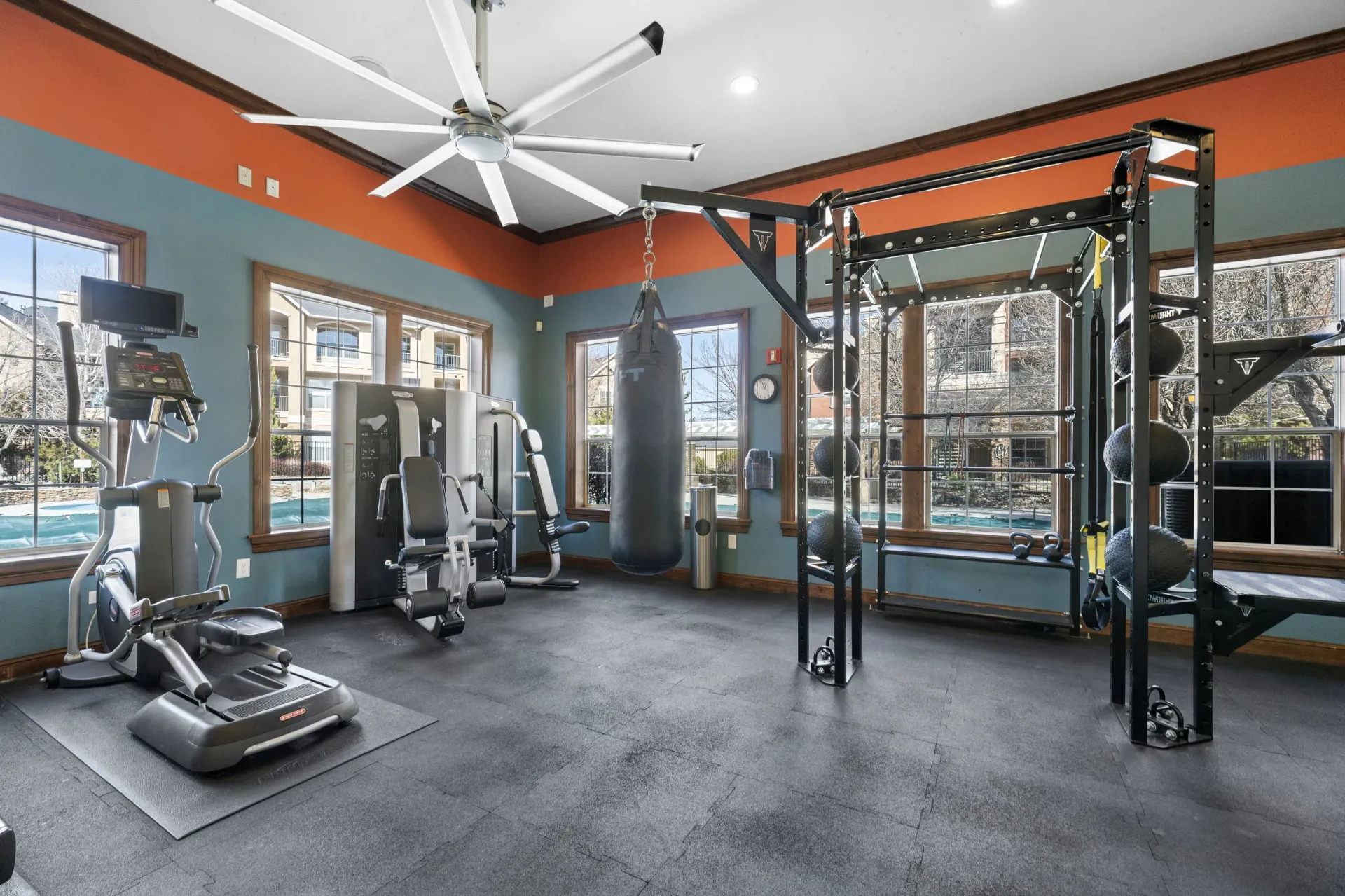 Well-equipped community gym with cardio machines, weight rack, and a hanging punching bag.