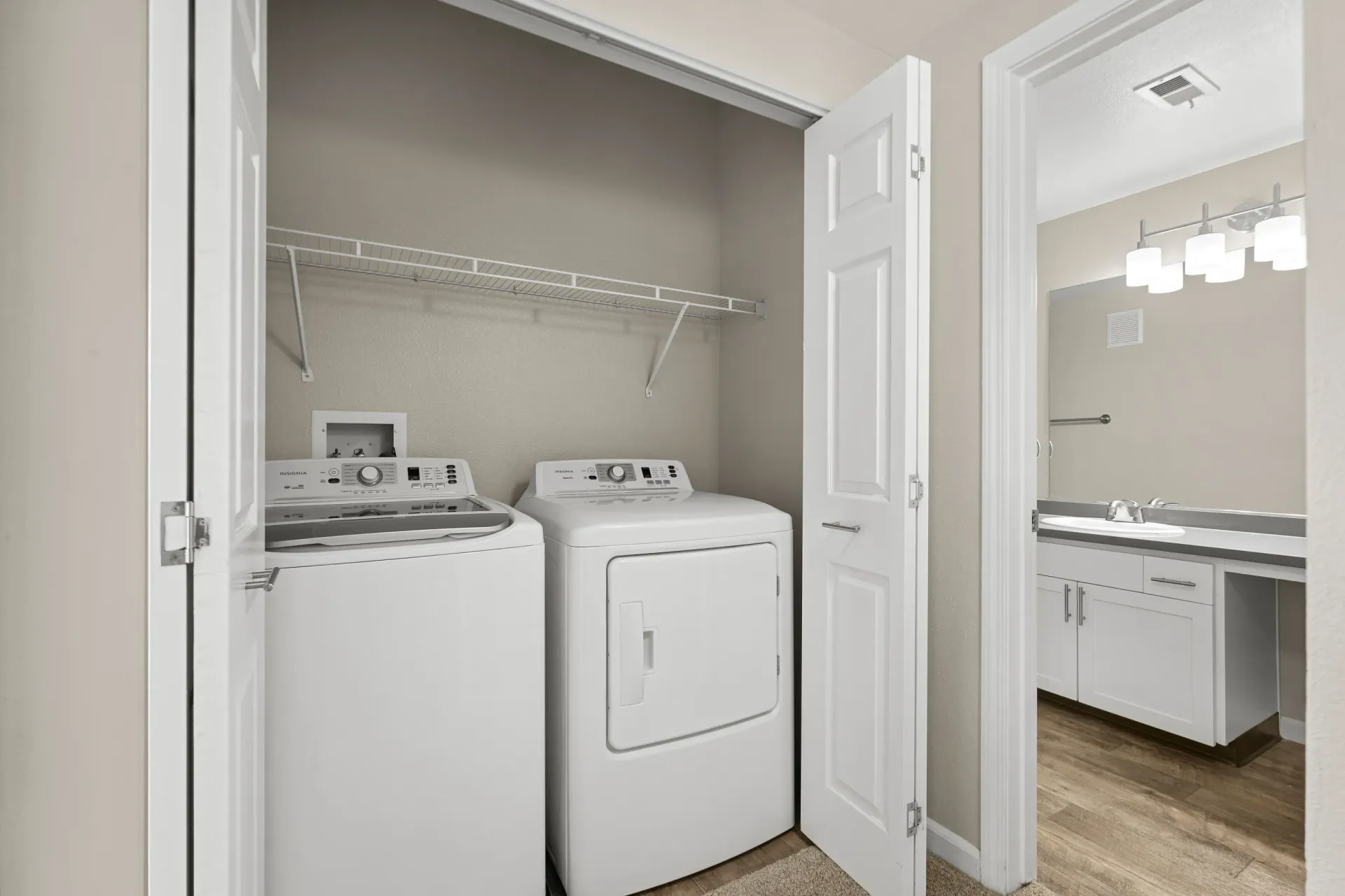 In-unit laundry closet with a washer and dryer; bathroom vanity visible.