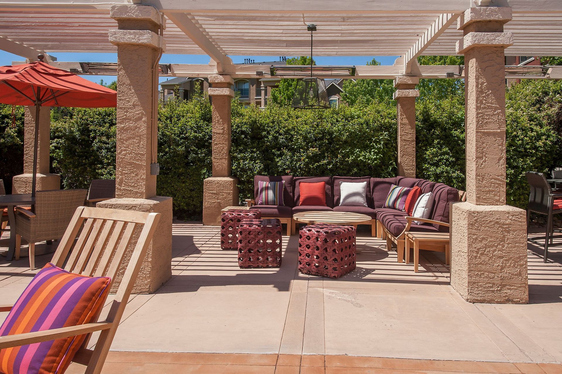 Outdoor community lounge with a cushioned sectional under a pergola.