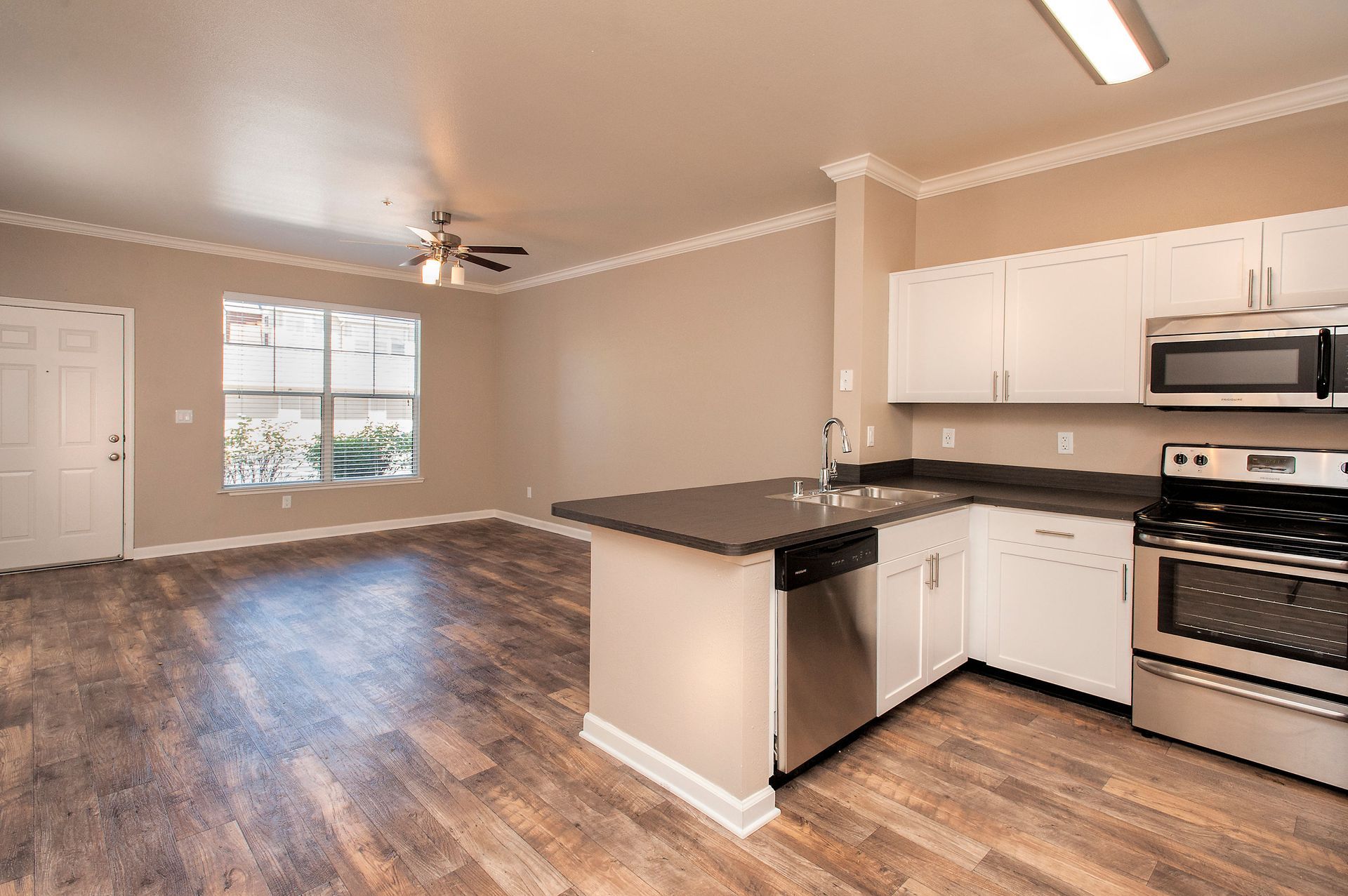 Open-concept kitchen and living area with an island, white cabinets, and stainless steel appliances.