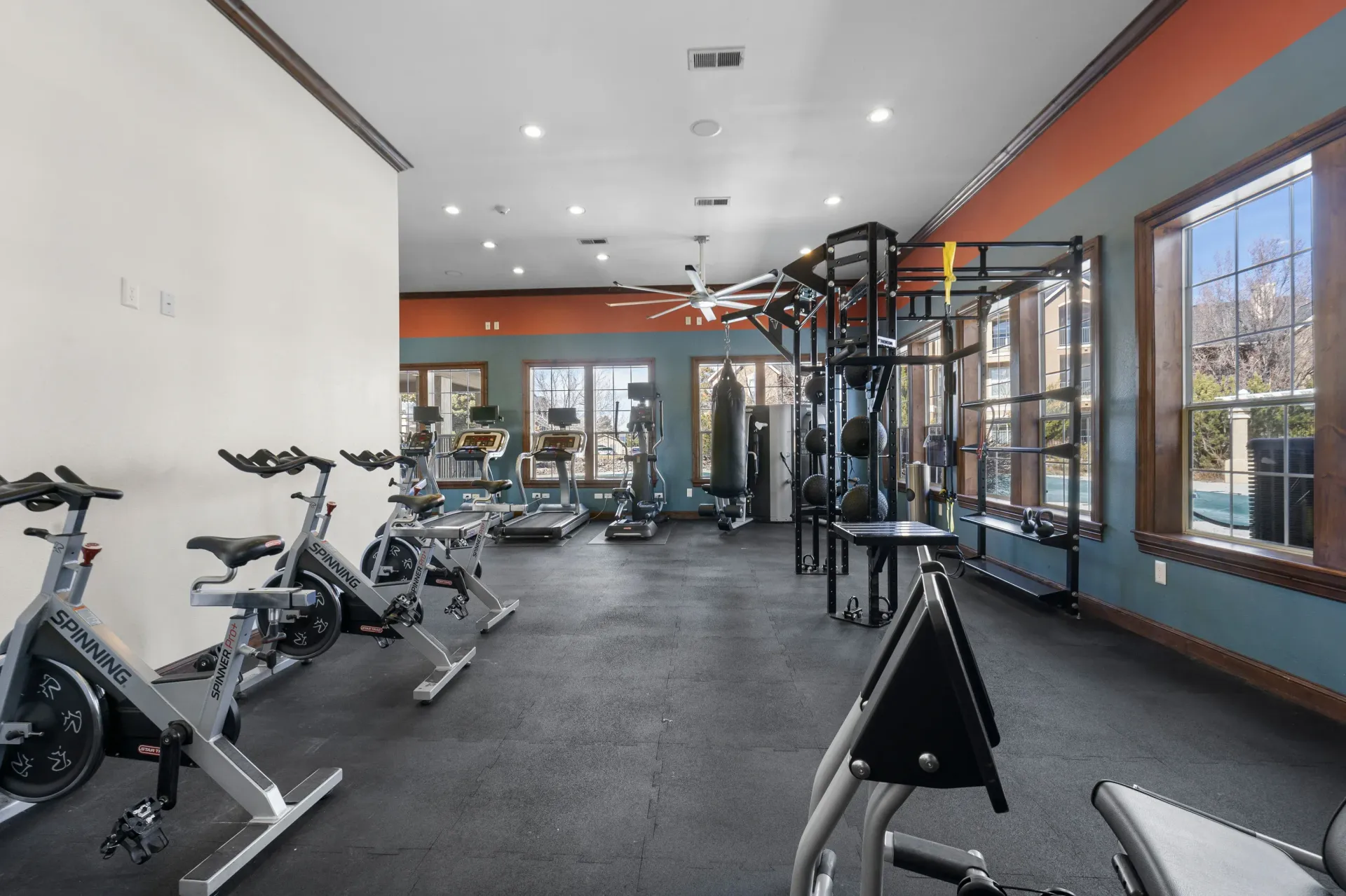 Indoor community gym with cardio machines, free weights, and a large window wall.