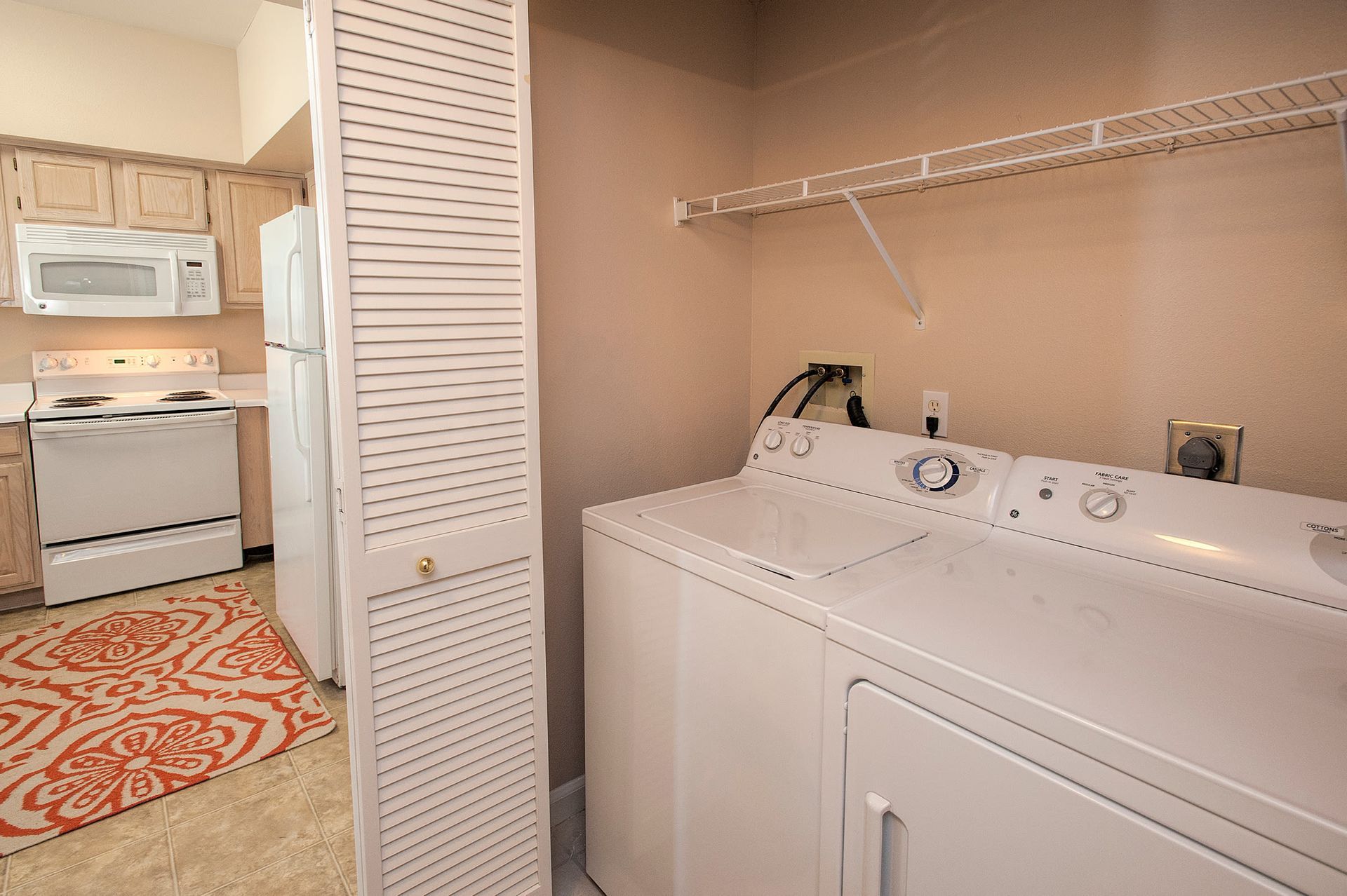 In-unit laundry closet with washer and dryer beside kitchen appliances.