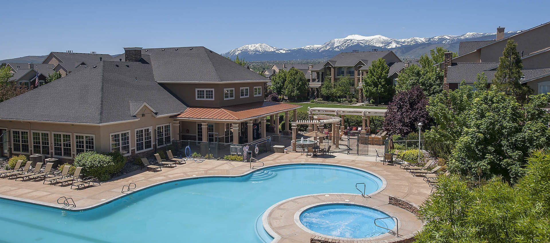 Outdoor pool with lounge chairs and a clubhouse at an apartment community.