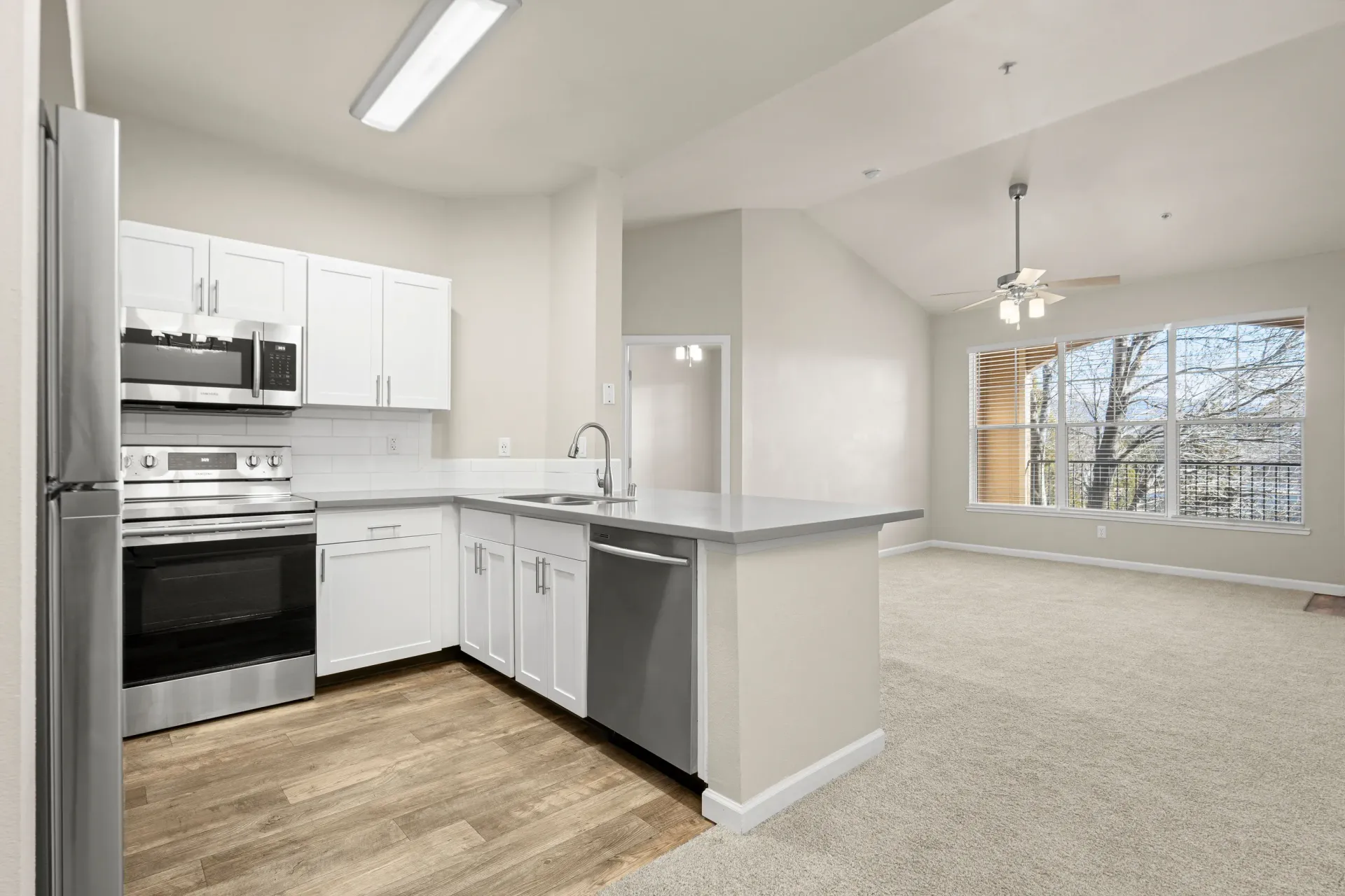 Open-concept kitchen with white cabinets, stainless-steel appliances, and island.