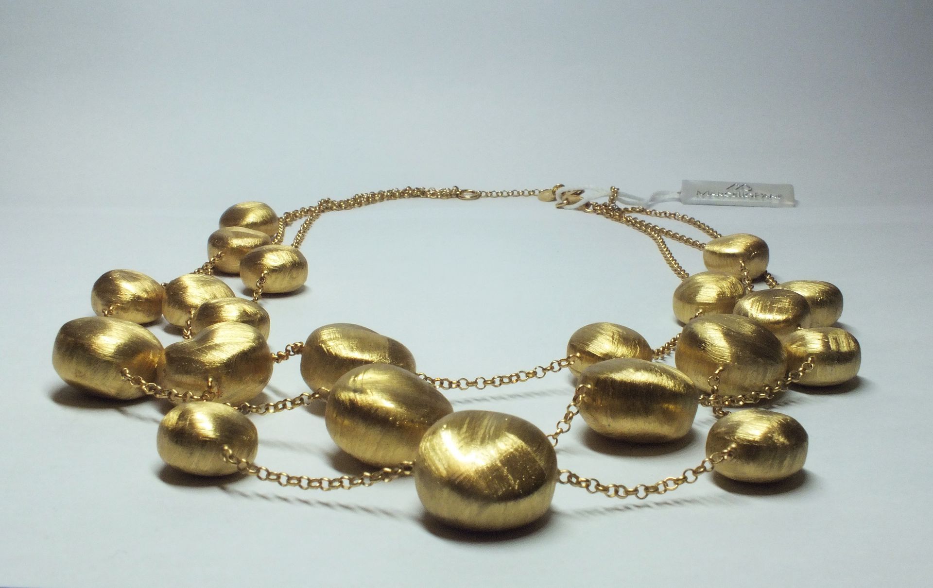Una collana d'oro con tante perle d'oro su una catena