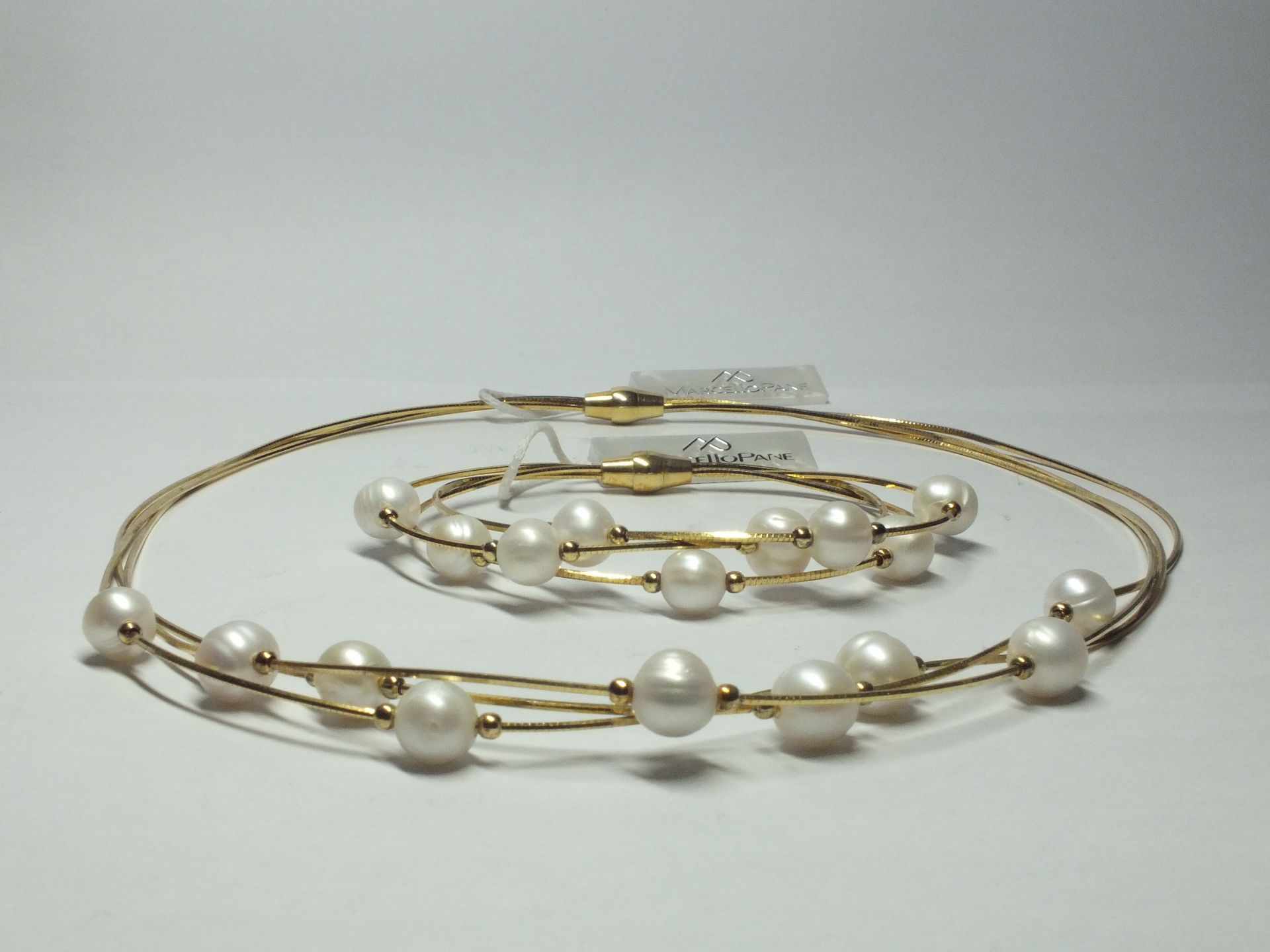 Una collana e un braccialetto con perle su una superficie bianca