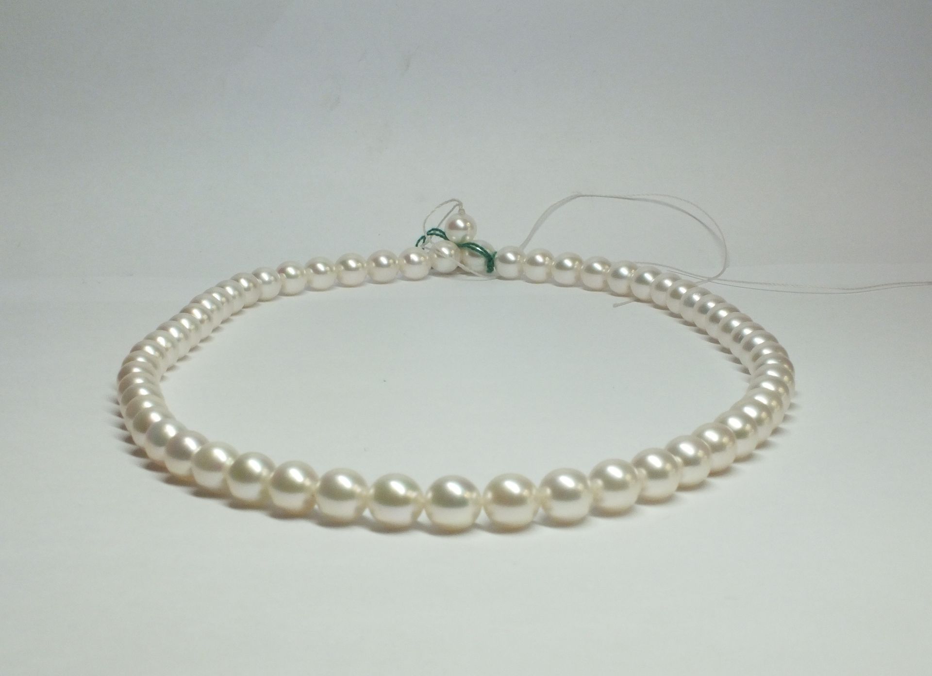 Una collana di perle bianche su una superficie bianca