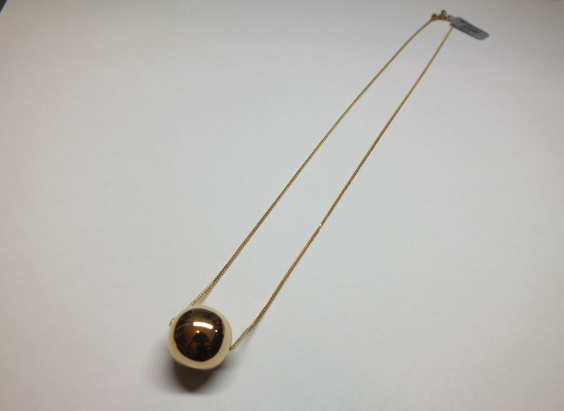 Una collana con una pallina marrone su una catena d'oro