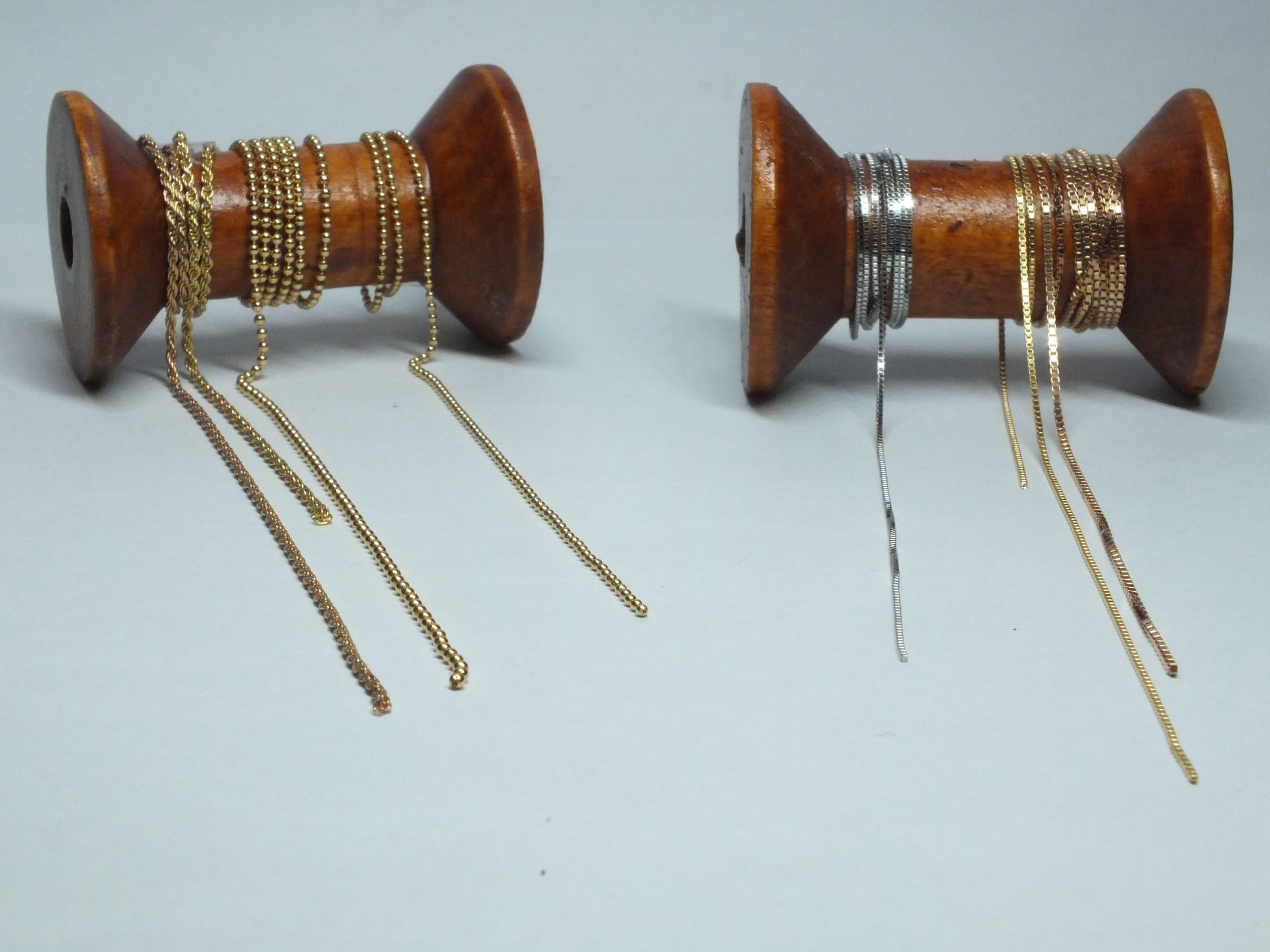 Due rocchetti di legno con catene d'oro e d'argento su di essi