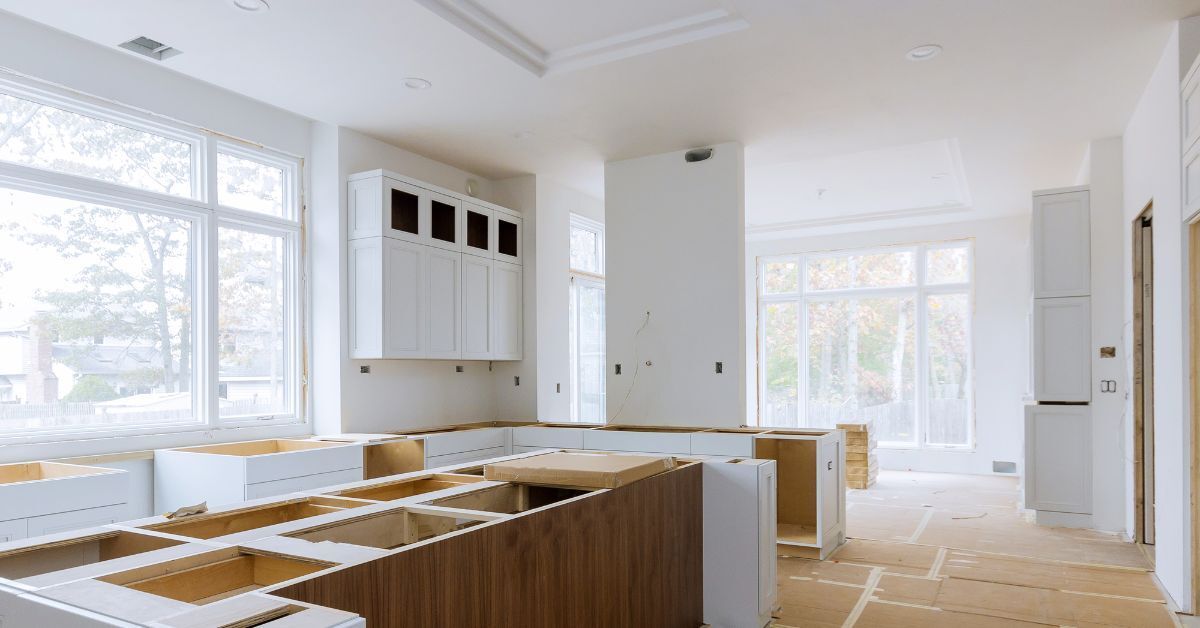 a kitchen under construction with white cabinets and wooden counter tops .