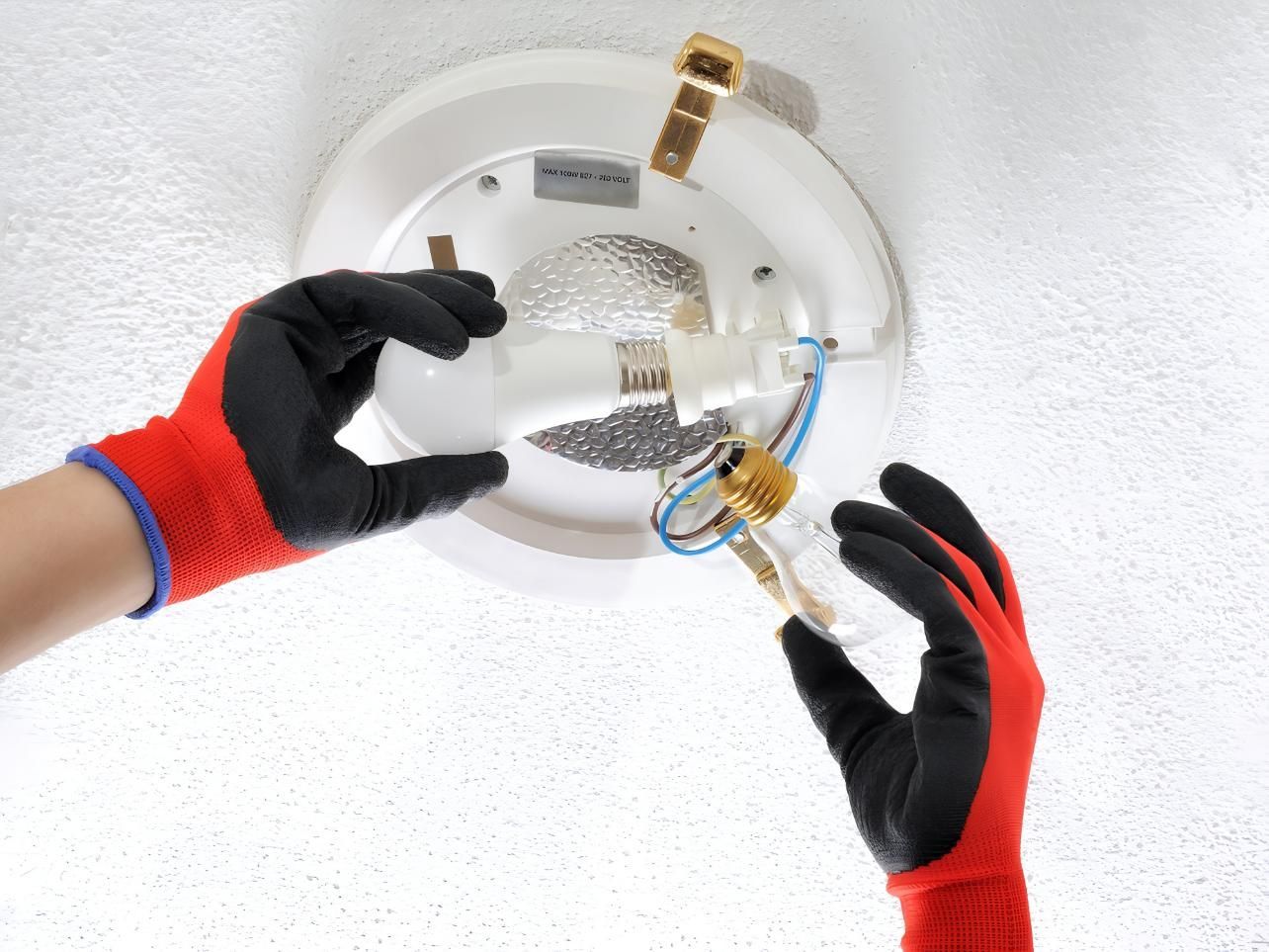 Hands in Red Gloves Replace a Lightbulb — J&C Electrical Services in Nebo, QLD