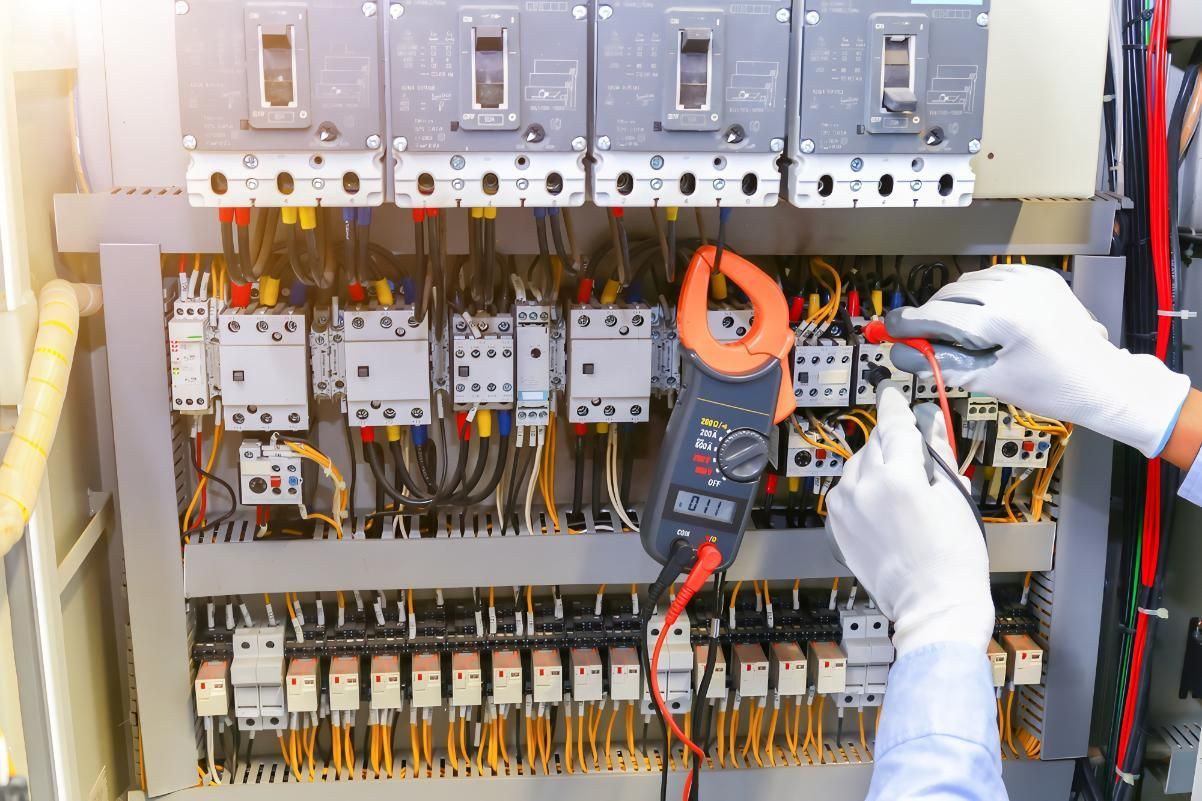 Electrician With Gloved Hands Using a Multimeter to Test Electrical Panel — J&C Electrical Services in Nebo, QLD