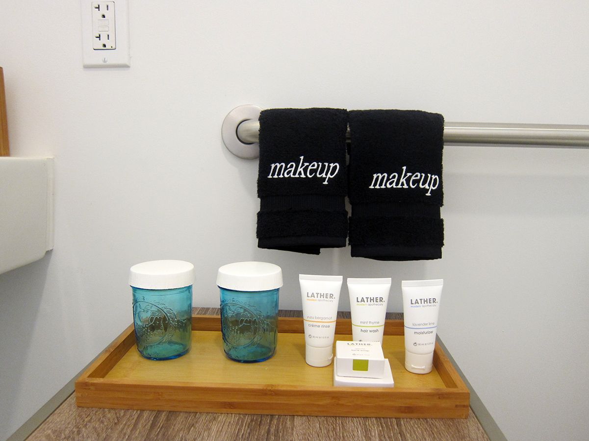 A wooden tray with two blue glass jars, three small white tubes, and a soap bar, below two black 