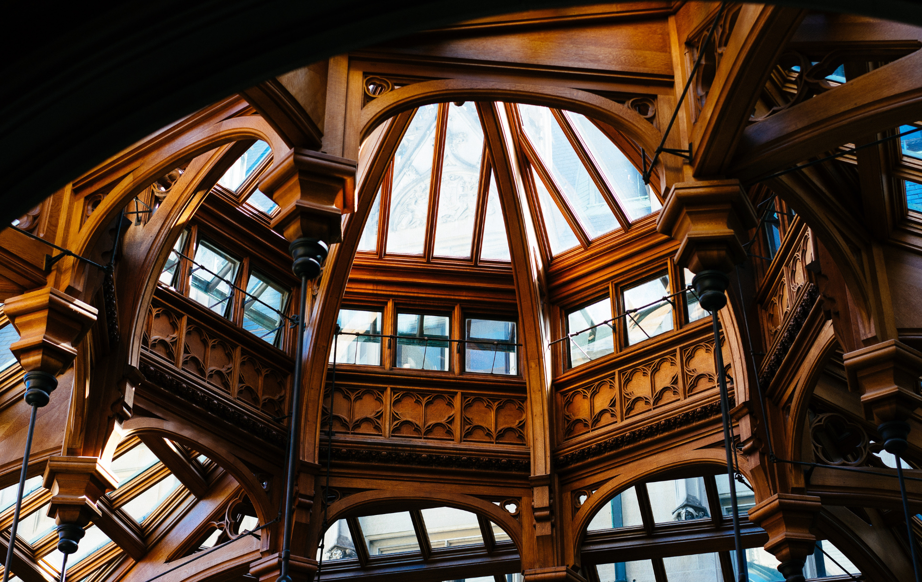 Ornate, wooden interior with arched ceilings and windowed roof. Brown wood with glass windows and natural light.