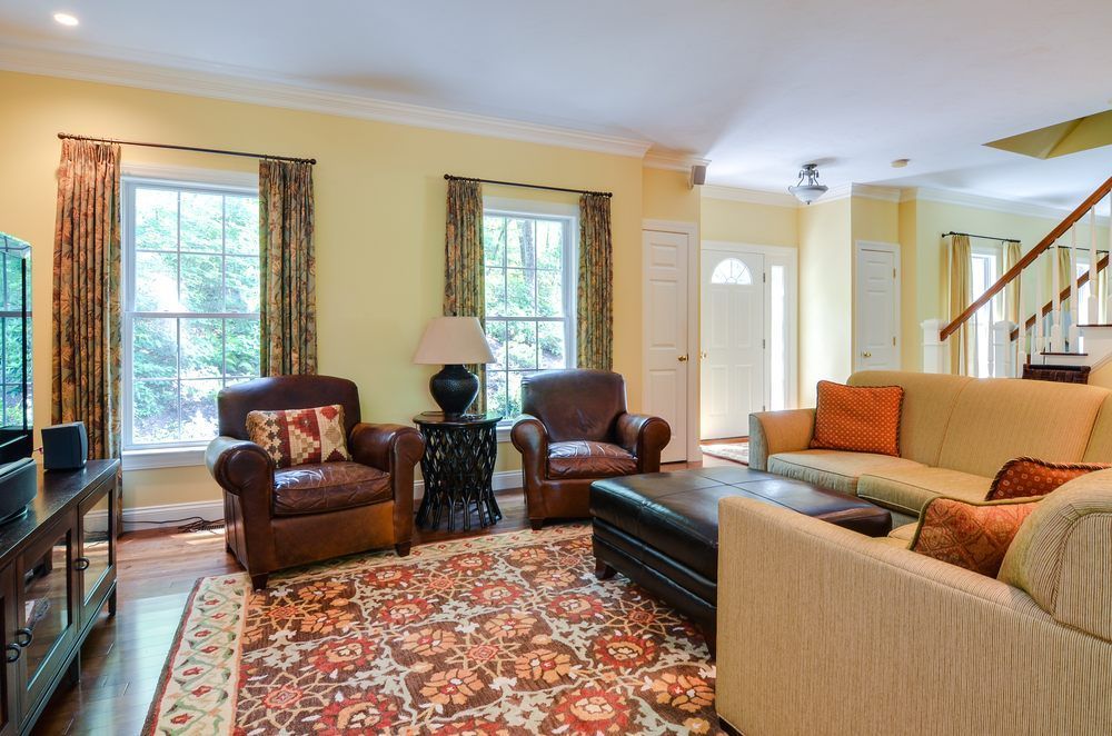 A living room with a couch , chairs , and a rug.