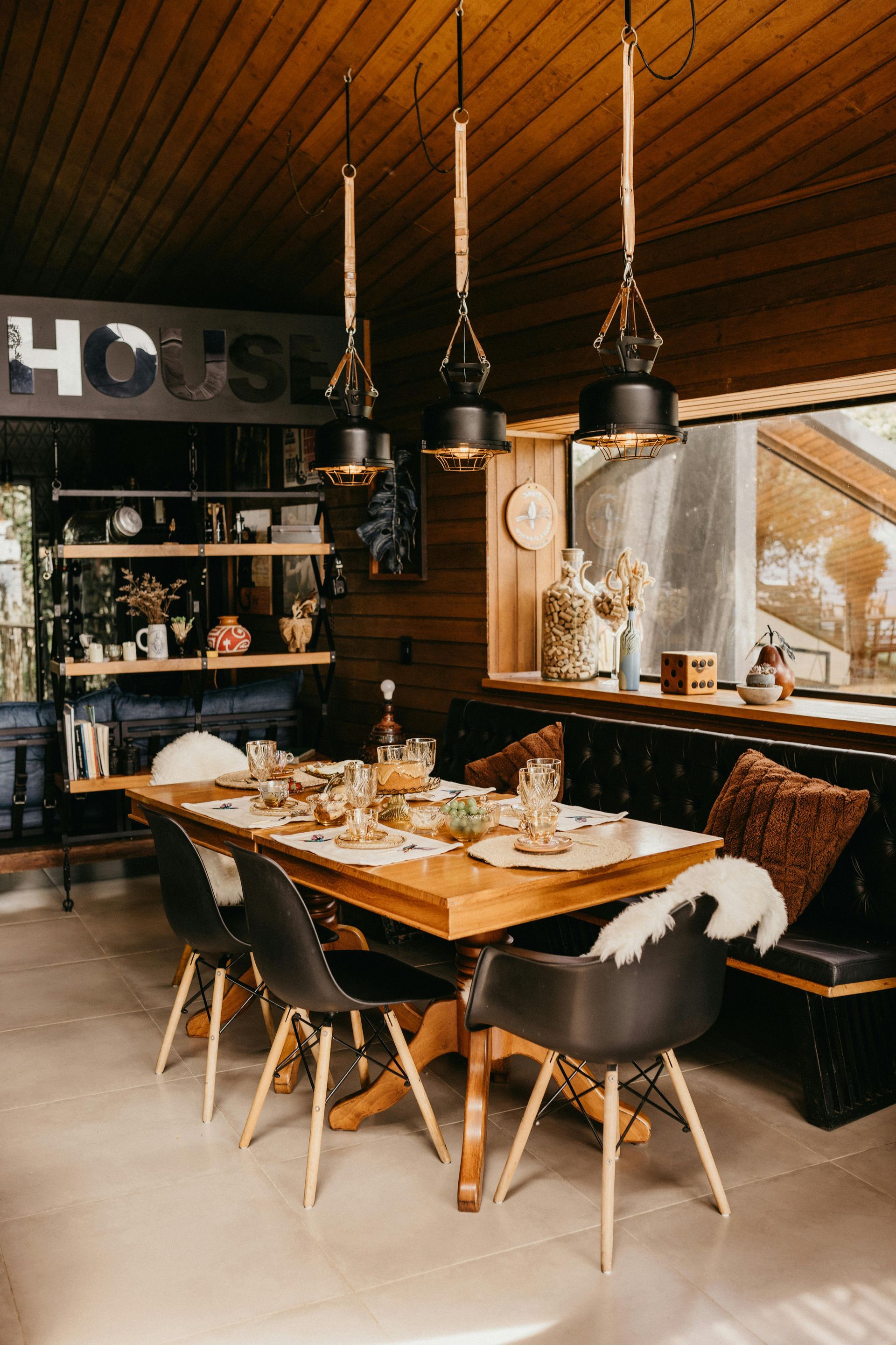 Dining room with wooden table, black chairs, leather bench, and pendant lights.