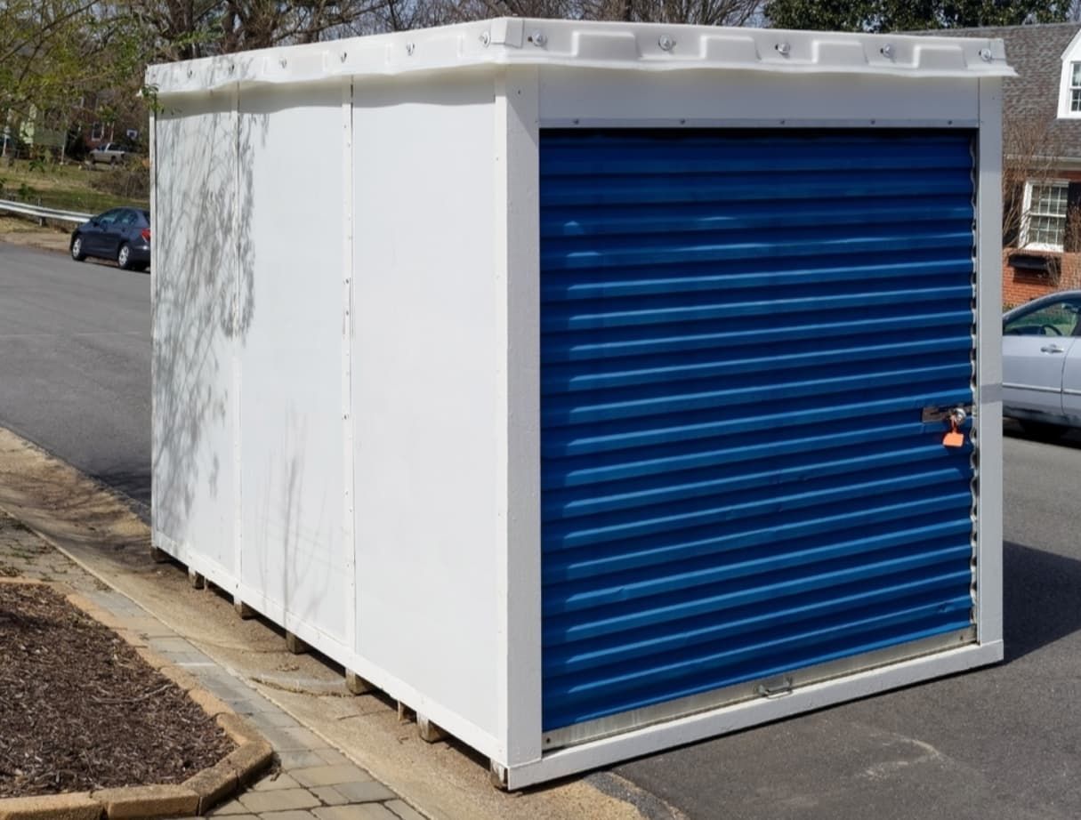 A White Storage Unit With Blue Roll-up Door On A Street — Gantic Removals & Storage in Brisbane, QLD